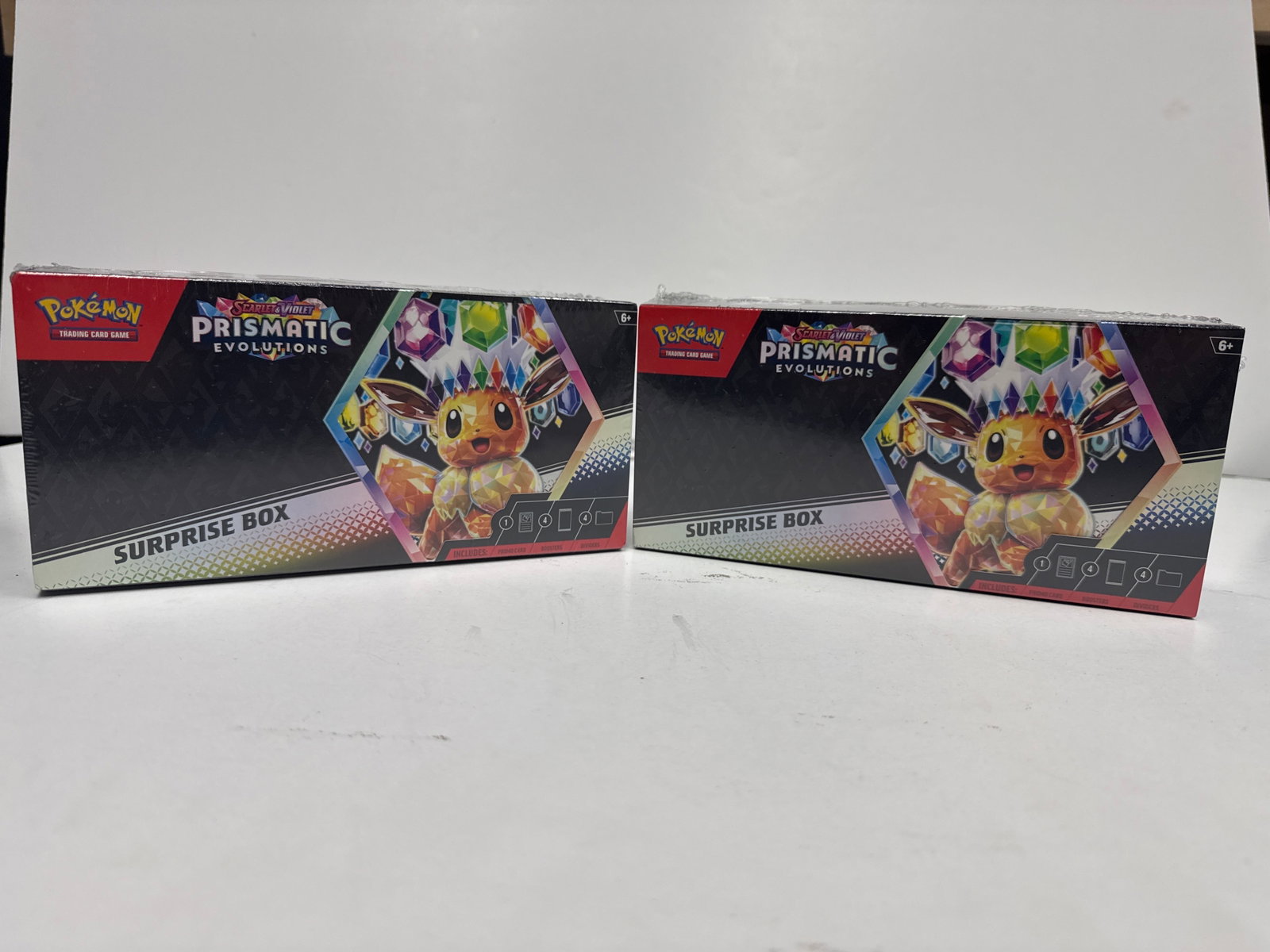Pokemon TCG Scarlet & Violet - Prismatic Evolutions Surprise Box: This lot includes two Pokemon TCG Scarlet & Violet - Prismatic Evolutions Surprise Boxes. Each box contains 1 of 9 randomly selected foil promo cards with a special logo, featuring Eevee or one of its
