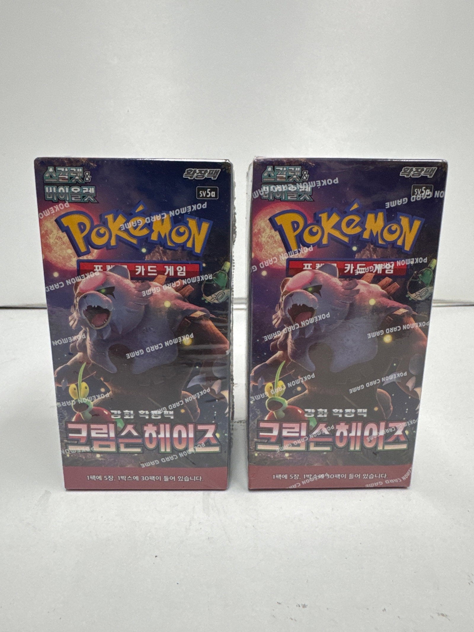 Two Pokemon Card Game Booster Boxes - Korean Version: This lot features two sealed booster boxes for the Pokemon Card Game, Korean version. The boxes are for the 'Crimson Haze' expansion and each contains 5 packs with 10 cards per pack.