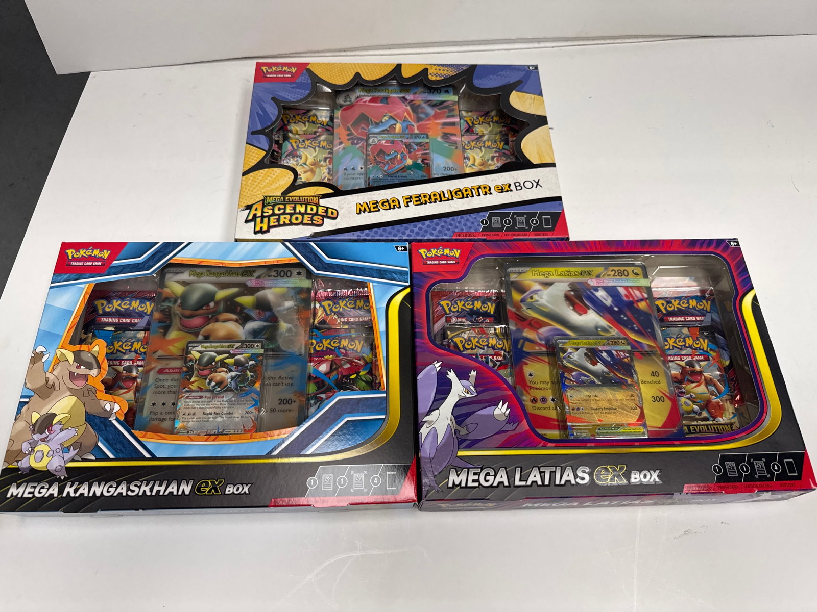 Pokemon TCG Mega Evolution EX Box Set: Mega Feraligatr, Mega Kangaskhan, Mega Latias: This lot features three Pokemon Trading Card Game Mega Evolution EX boxes: Mega Feraligatr EX, Mega Kangaskhan EX, and Mega Latias EX. Each box contains booster packs and promotional cards, offering a