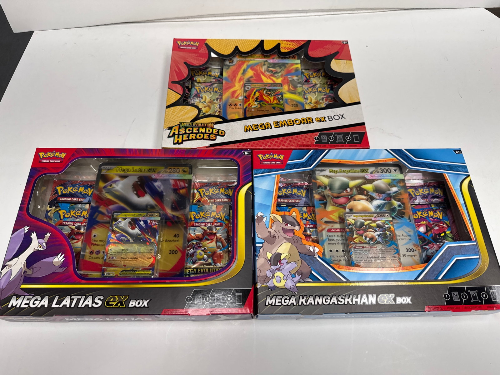 Pokemon Mega Evolution Trading Card Game Boxes: This lot includes three Pokemon Mega Evolution trading card game boxes: Mega Emboar EX Box, Mega Latias EX Box, and Mega Kangaskhan EX Box. Each box contains booster packs and promotional cards, offer