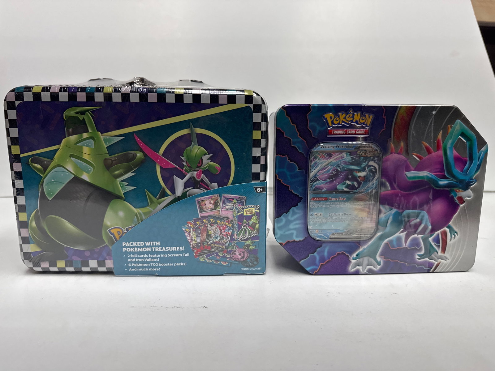 Pokemon Trading Card Game Tins: This lot includes two Pokemon Trading Card Game tins. The larger tin features artwork with Pokemon like Tyranitar and Gardevoir, and is packed with Pokemon treasures including 2 foil promo cards, 6