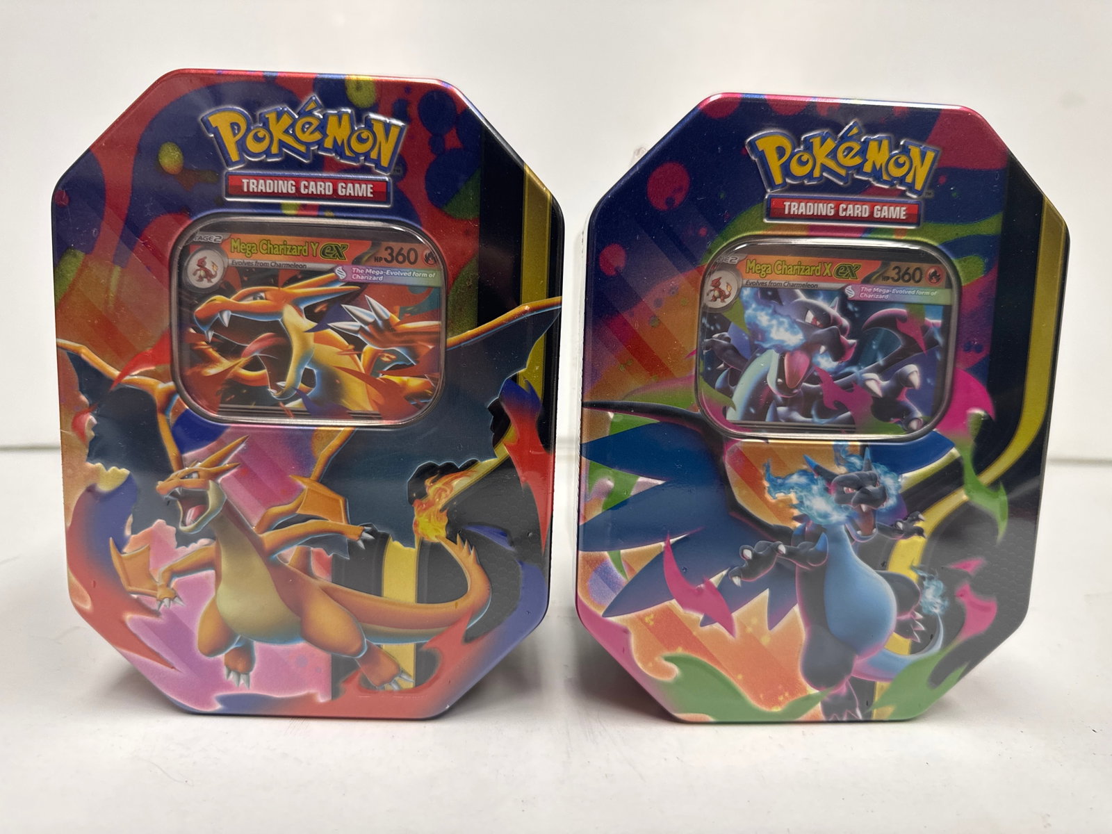 Pokemon Trading Card Game Mega Charizard EX Tins (2-Pack): This lot features two Pokemon Trading Card Game tins, each showcasing Mega Charizard EX. The tins are designed to hold booster packs and promotional cards, featuring vibrant artwork of Charizard in it