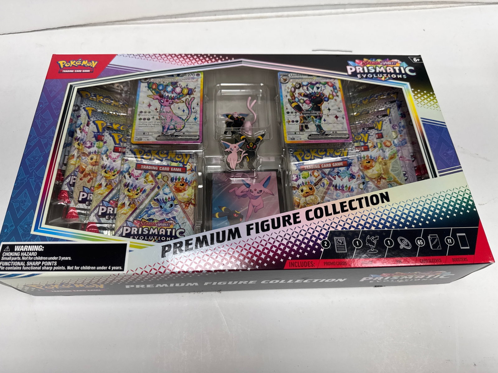 Pokemon Scarlet & Violet Prismatic Evolutions Premium Figure Collection Box: This Pokemon Scarlet & Violet Prismatic Evolutions Premium Figure Collection Box includes two promo cards, a pin, card sleeves, and booster packs. It features Espeon and Umbreon on the box art.