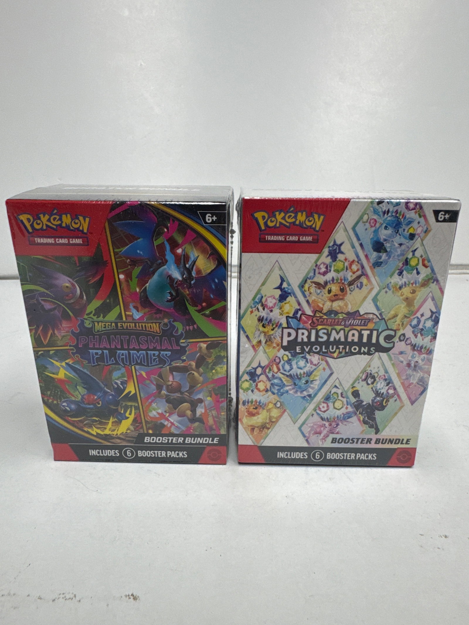 Pokemon TCG Booster Bundle - Mega Evolution Phantasmals Flames & Scarlet & Violet Prismatic: This lot includes two Pokemon Trading Card Game Booster Bundles. One is the Mega Evolution Phantasmals Flames expansion, featuring Mega Charizard and other powerful Pokemon. The second is the Scarlet 
