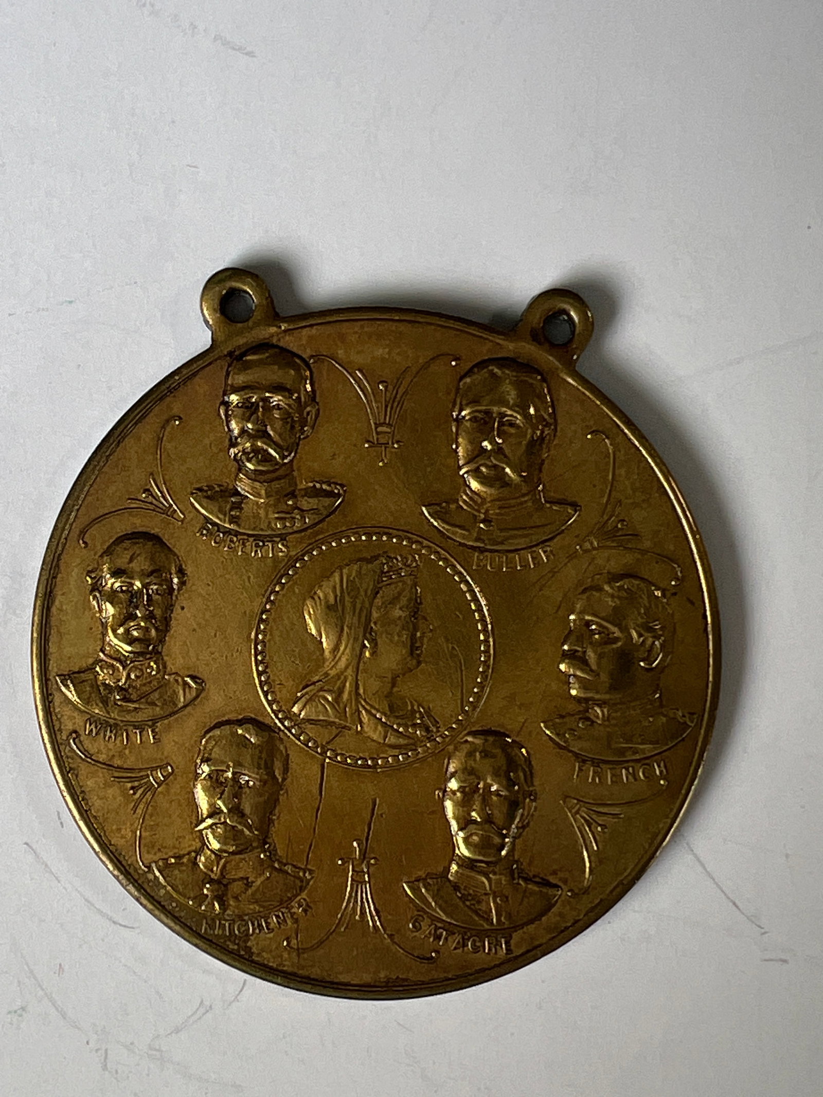 Commemorative Medallion with Portraits and Coat of Arms: A commemorative medallion featuring a central portrait surrounded by six other portraits on one side. The reverse displays a coat of arms. The medallion is made of a bronze-colored metal and has two