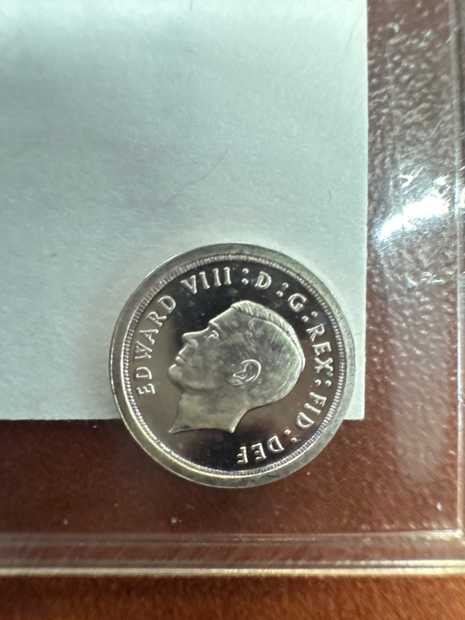 Edward VIII 1936 Silver Proof Coin: A rare 1936 silver proof coin featuring the effigy of Edward VIII on the obverse and the numeral '1' within a wreath on the reverse. This coin is a significant historical artifact from a