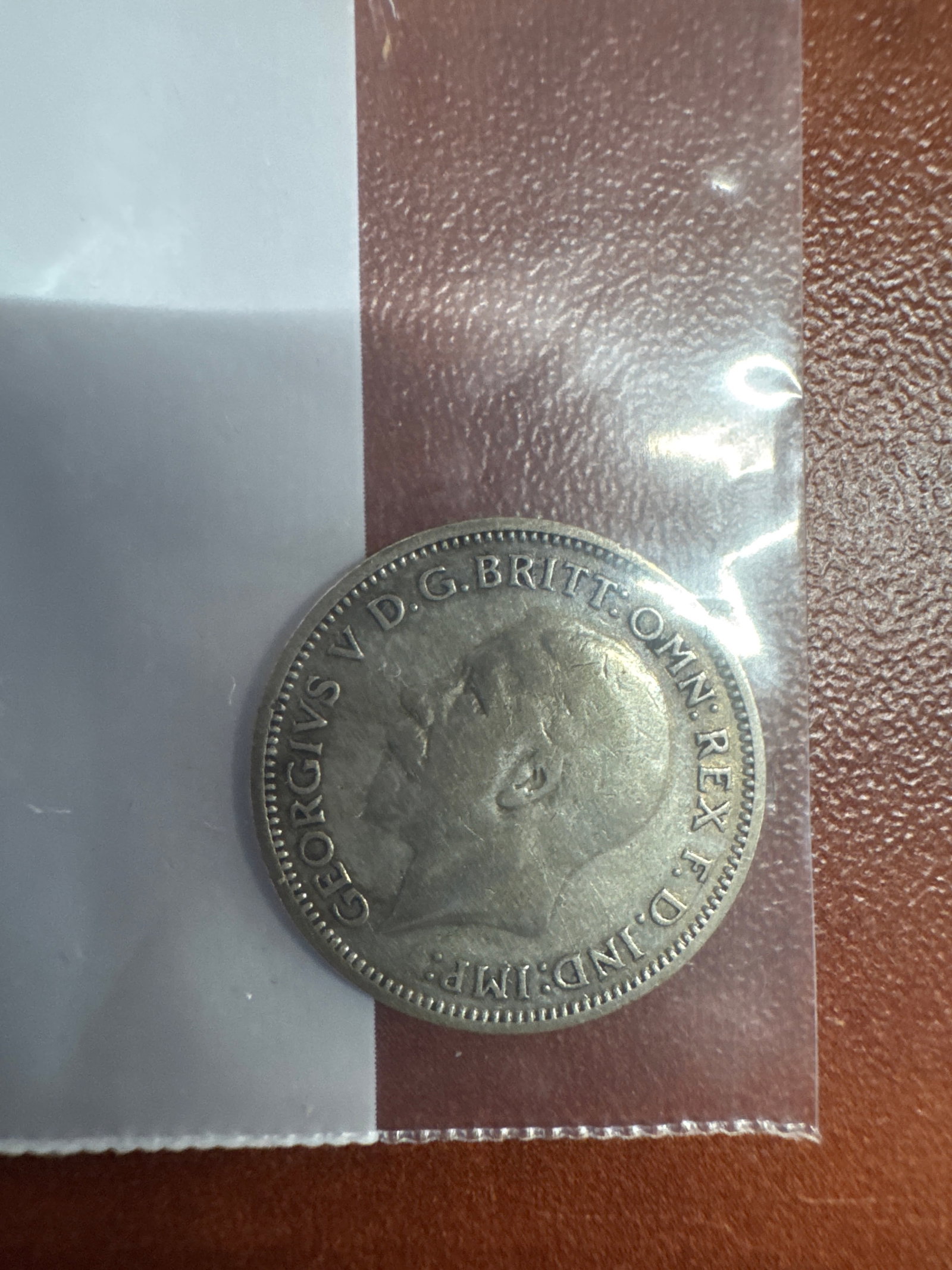 1936 British Sixpence Coin: A vintage 1936 British sixpence coin featuring King George V on the obverse and a floral design on the reverse. 