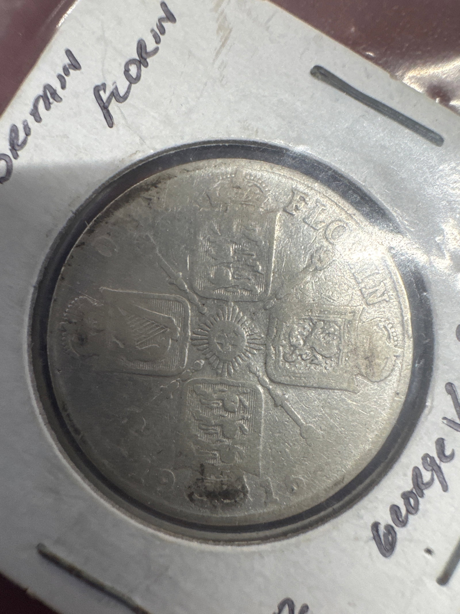 1916 British Florin Coin - George V: A British Florin coin from 1916, featuring King George V on the obverse and the Royal Arms on the reverse. The coin shows signs of wear consistent with its age.