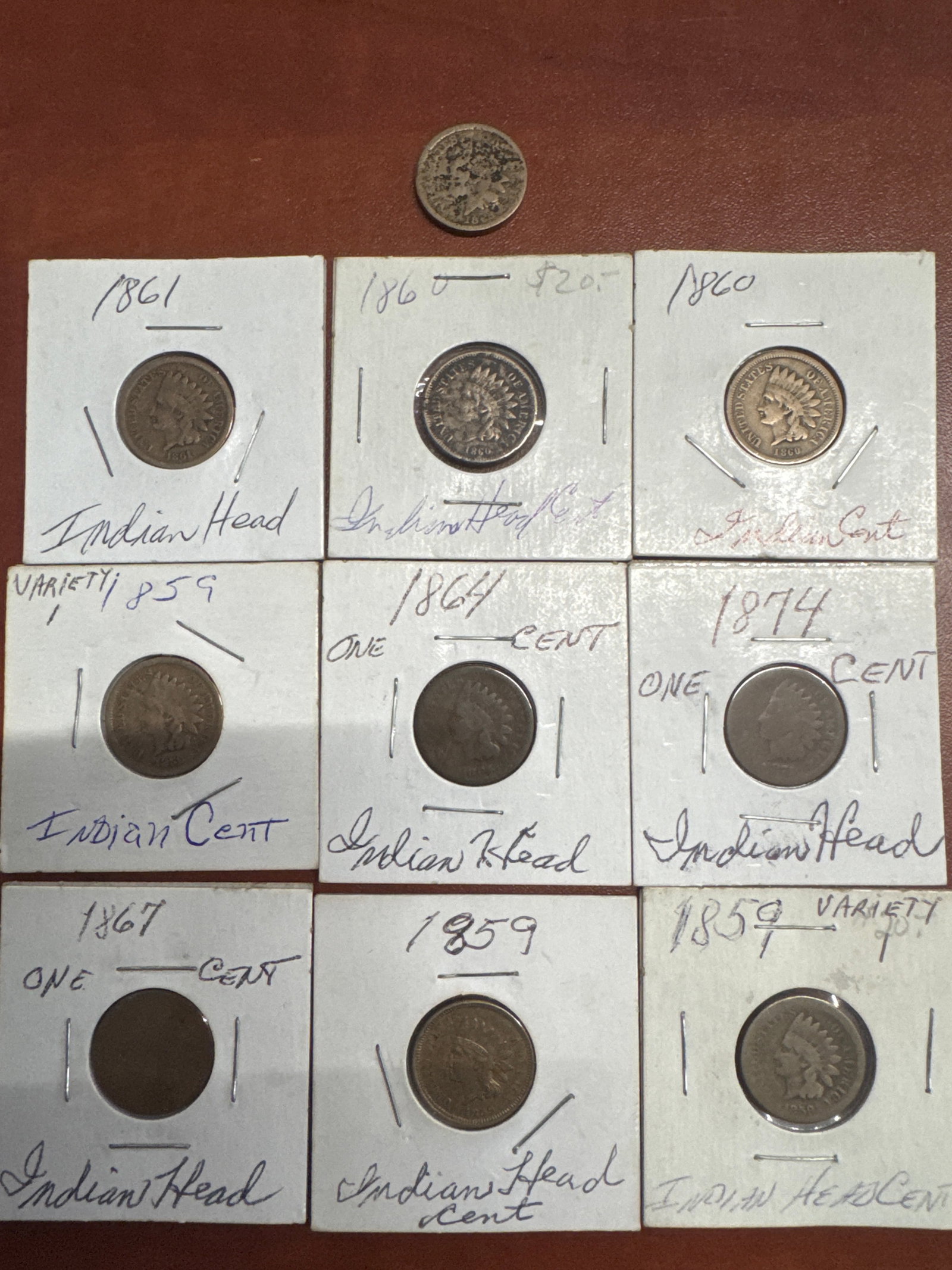 Collection of 10 Indian Head Pennies: A collection of ten Indian Head pennies, dated from 1859 to 1874. Each coin is housed in a protective sleeve with handwritten annotations indicating the year and variety. The collection includes a var