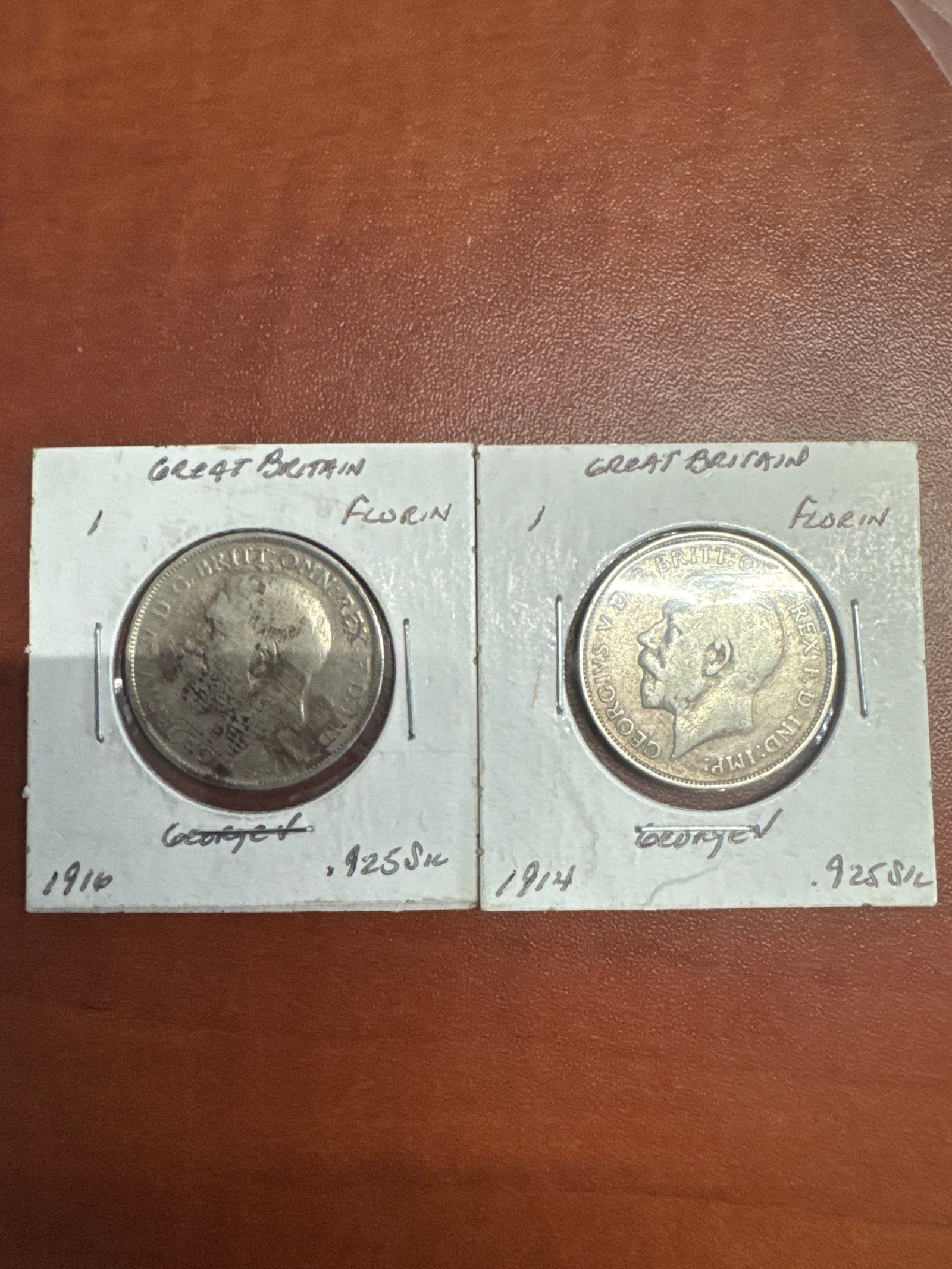 Two Great Britain Florin Coins: 1916 and 1914: This lot features two Great Britain Florin coins. The first coin is dated 1916 and is made of .925 silver. The second coin is dated 1914 and is also made of .925 silver. Both coins depict King George 