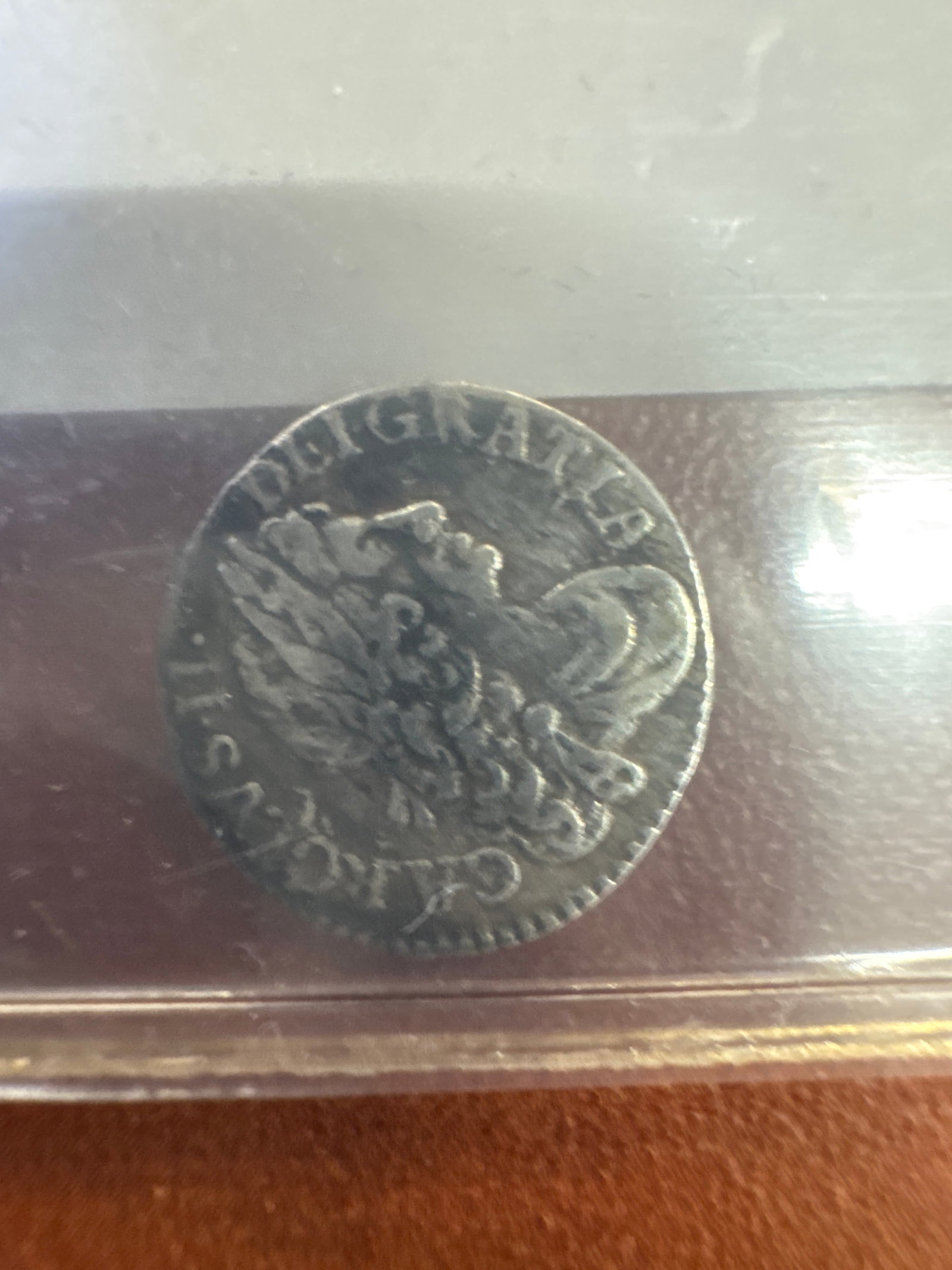 1679 English Silver 2 Pence Coin: A silver coin from 1679, featuring an eagle with outstretched wings on one side and a crowned emblem on the other. The coin exhibits wear consistent with its age.