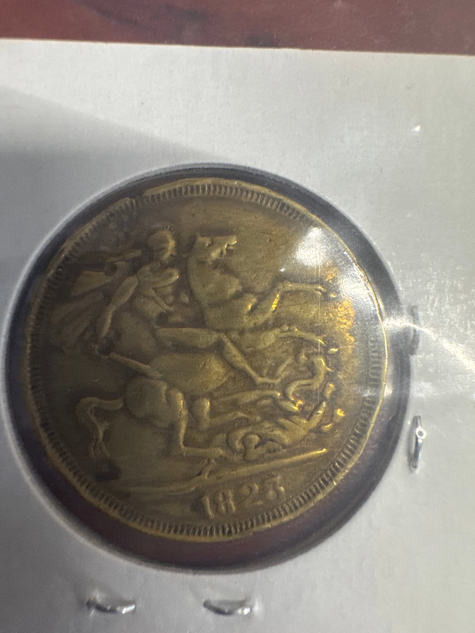 1823 George IV British Coin: A brass coin featuring a profile of King George IV on one side and St. George slaying a dragon on the other. The year 1823 is clearly visible.