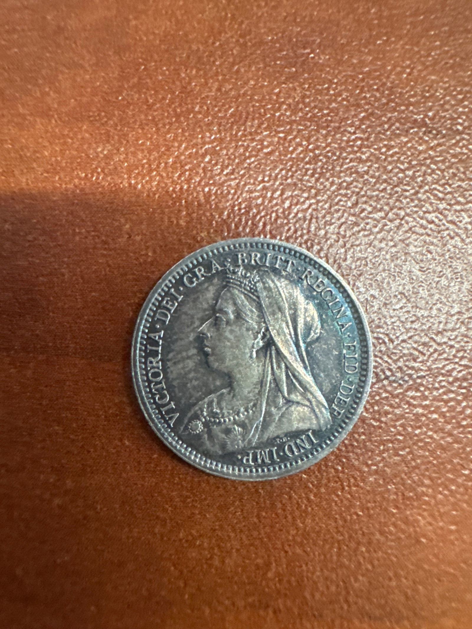 1899 Victorian Era Silver 3 Pence Coin: A silver coin from the Victorian era, dated 1899. The obverse features a profile of Queen Victoria, inscribed 'VICTORIA DEI GRATIA BRIT REGINA FID DEF IND IMP'. The reverse displays the numera