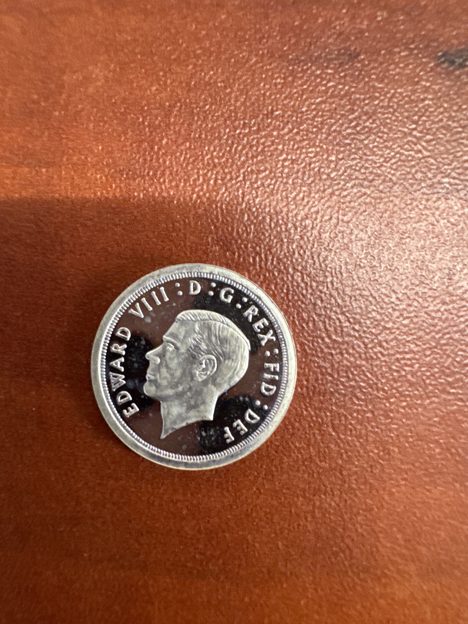 1936 Edward VIII Silver Proof 4 Pence Coin: A rare 1936 silver proof 4 pence coin featuring a profile of King Edward VIII on the obverse and the numeral '4' surrounded by a wreath and crown on the reverse. 