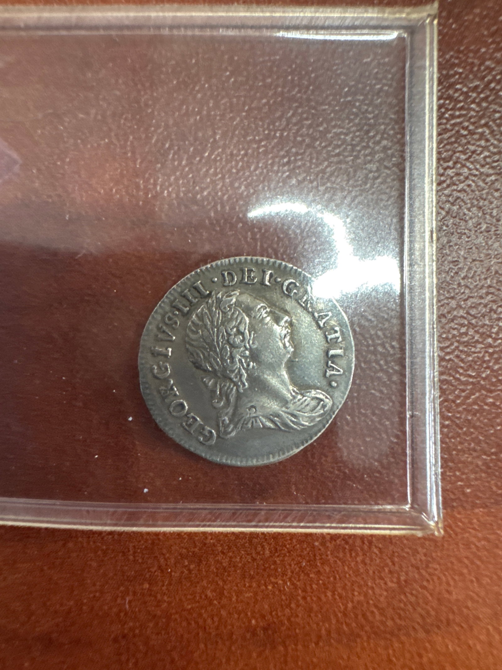George III Silver 2 Shilling Coin: A George III silver 2 shilling coin, featuring a profile portrait of the King on the obverse and the numeral '2' with a crown on the reverse. The coin shows signs of wear consistent with its a
