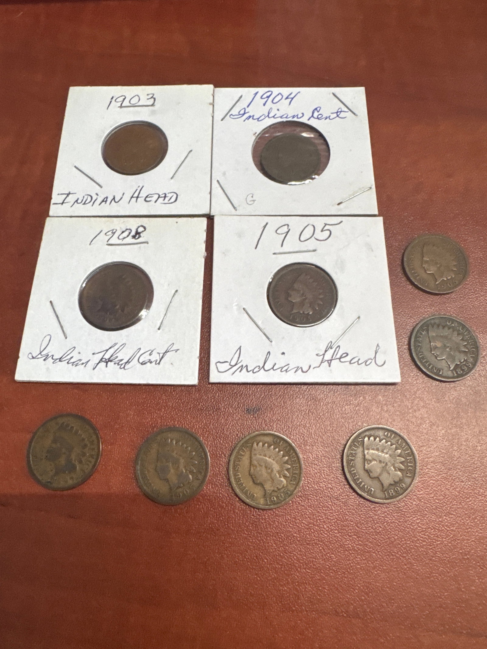 Collection of Indian Head Pennies: A collection of ten Indian Head pennies, dated 1903, 1904, 1905, 1908, and more. The coins are housed in protective sleeves, with some showing clear dates and designs, while others exhibit wear consis