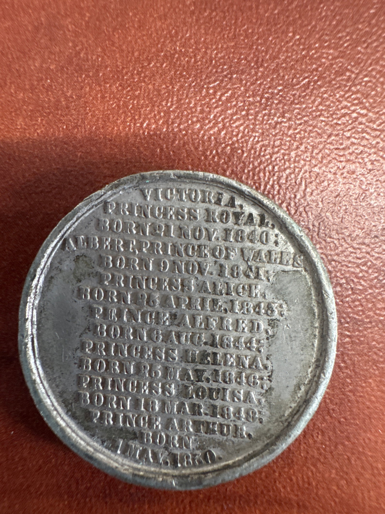 Victorian Royal Family Commemorative Medal: A silver-toned commemorative medal featuring portraits of the Victorian royal family. One side lists Victoria, Princess Royal, Prince Albert, and their children with their birth dates. The other side 