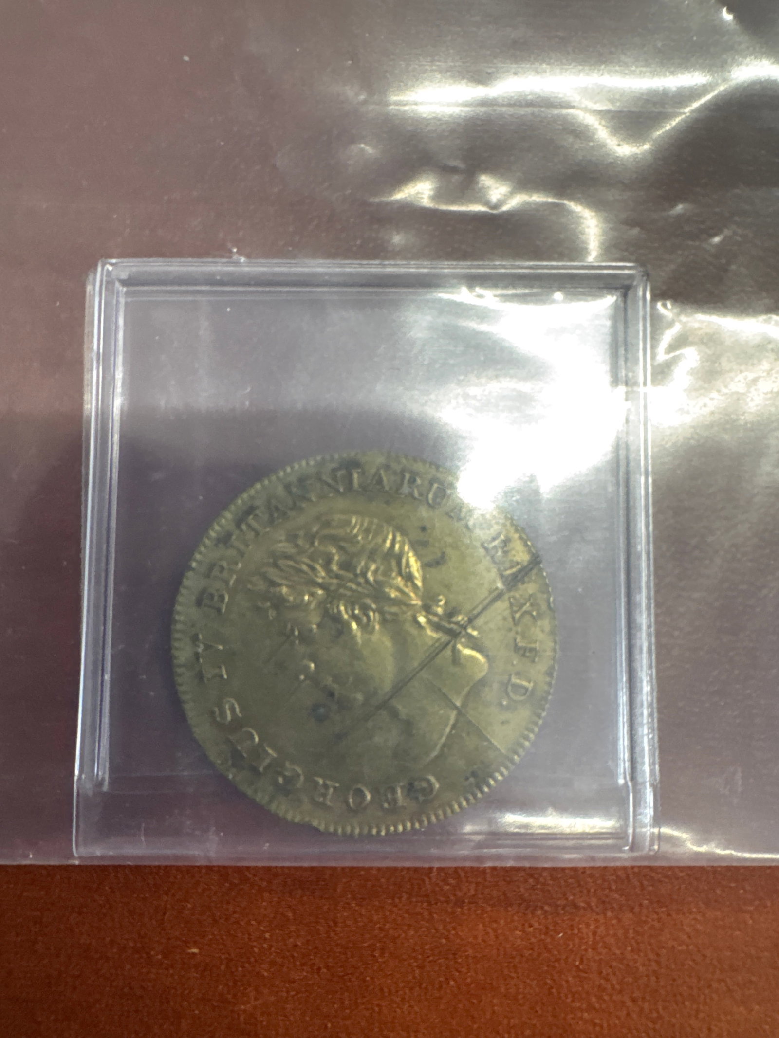 George IV Copper Coin: A George IV copper coin,. The obverse features a profile of King George IV, and the reverse displays a crowned shield with the royal arms, surrounded by a wreath. The coin shows signs of age