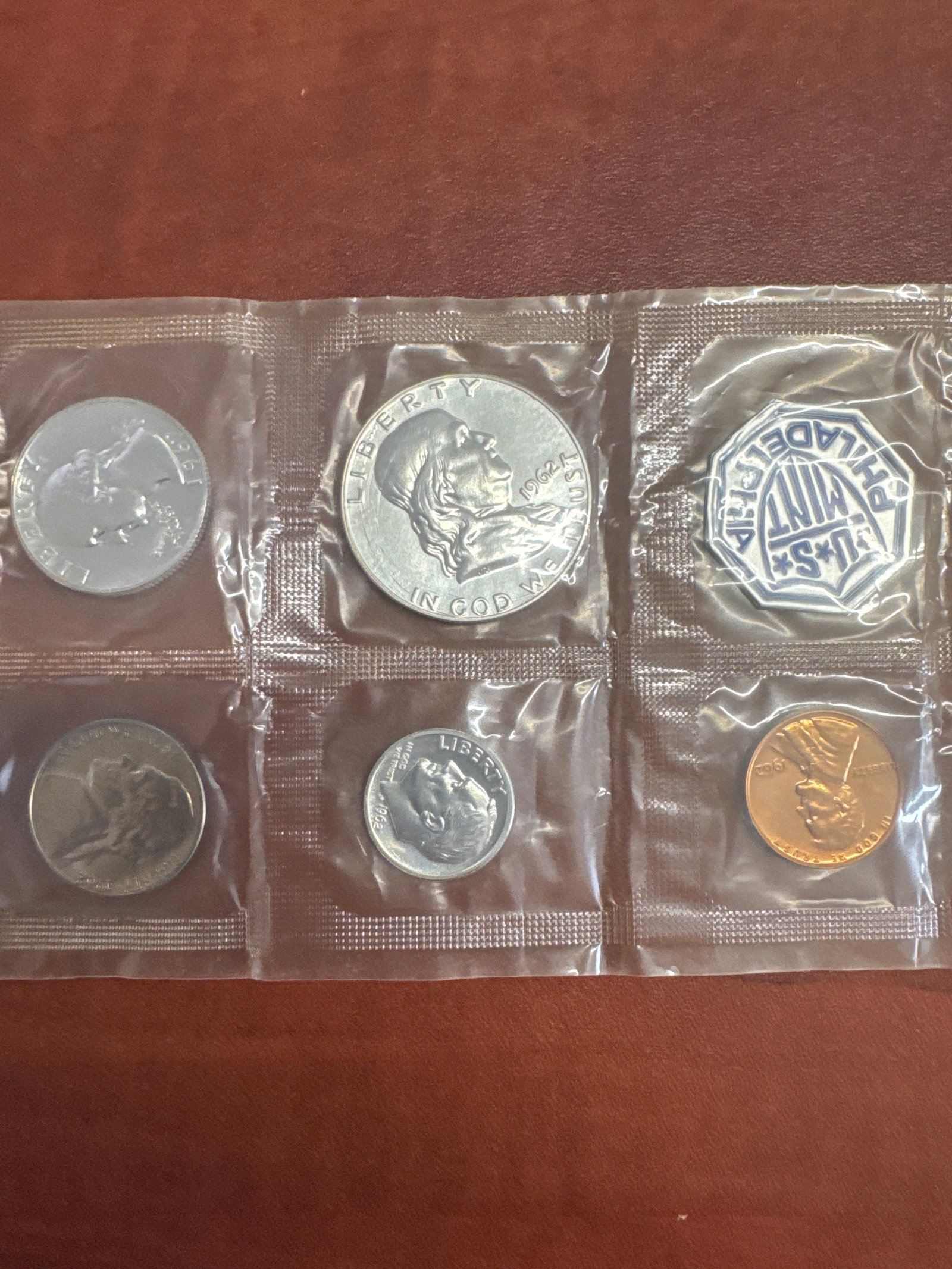 1962 US Mint Proof Set: This lot features a 1962 US Mint Proof Set, containing various denominations of coins sealed in protective plastic. The set includes a half dollar, dime, nickel, and penny, along with a special Philad