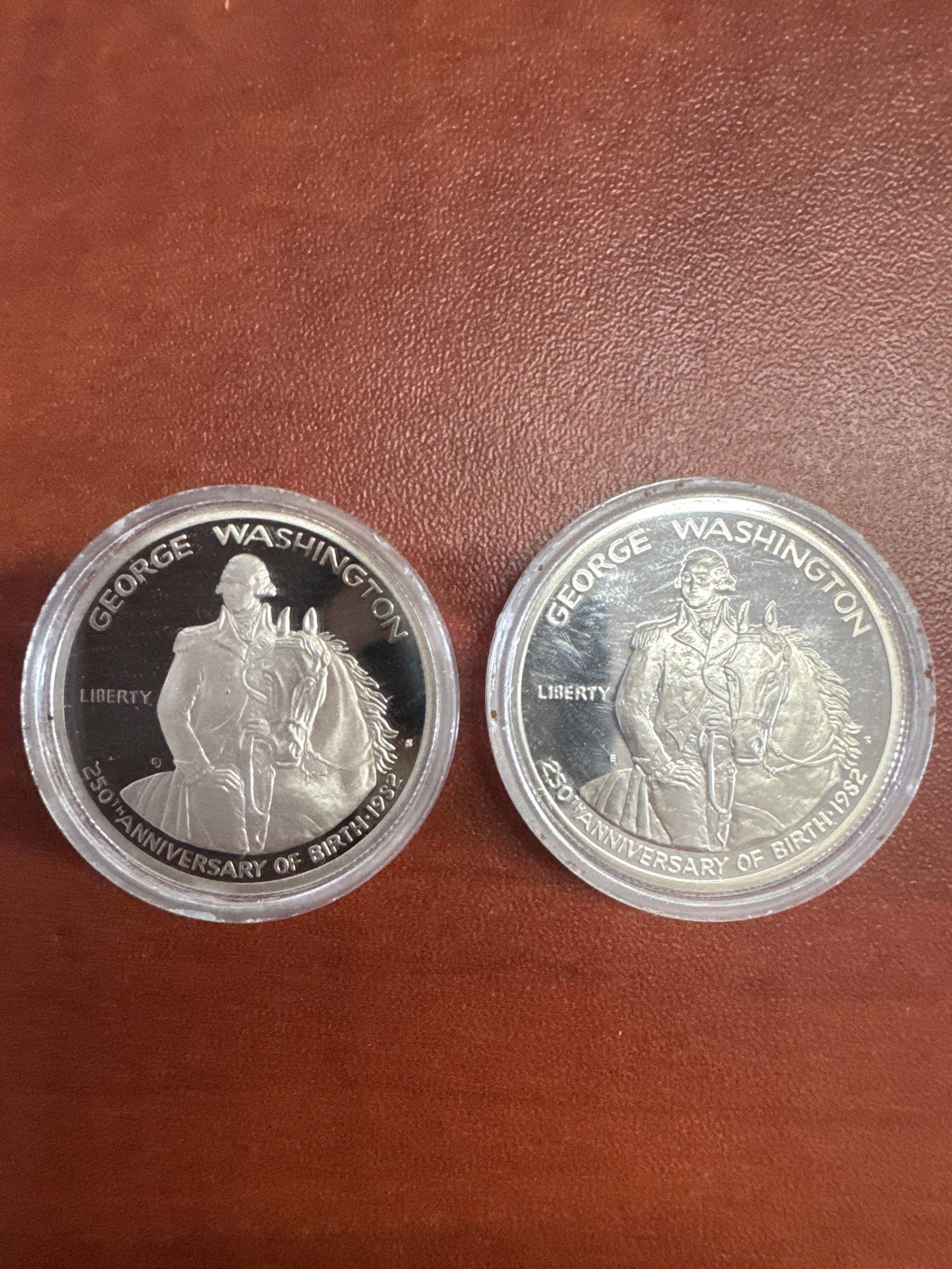 Two George Washington 250th Anniversary of Birth 1982 Half Dollar Coins: This lot features two commemorative half dollar coins celebrating the 250th anniversary of George Washington's birth in 1982. One side depicts George Washington on horseback. The reverse side show