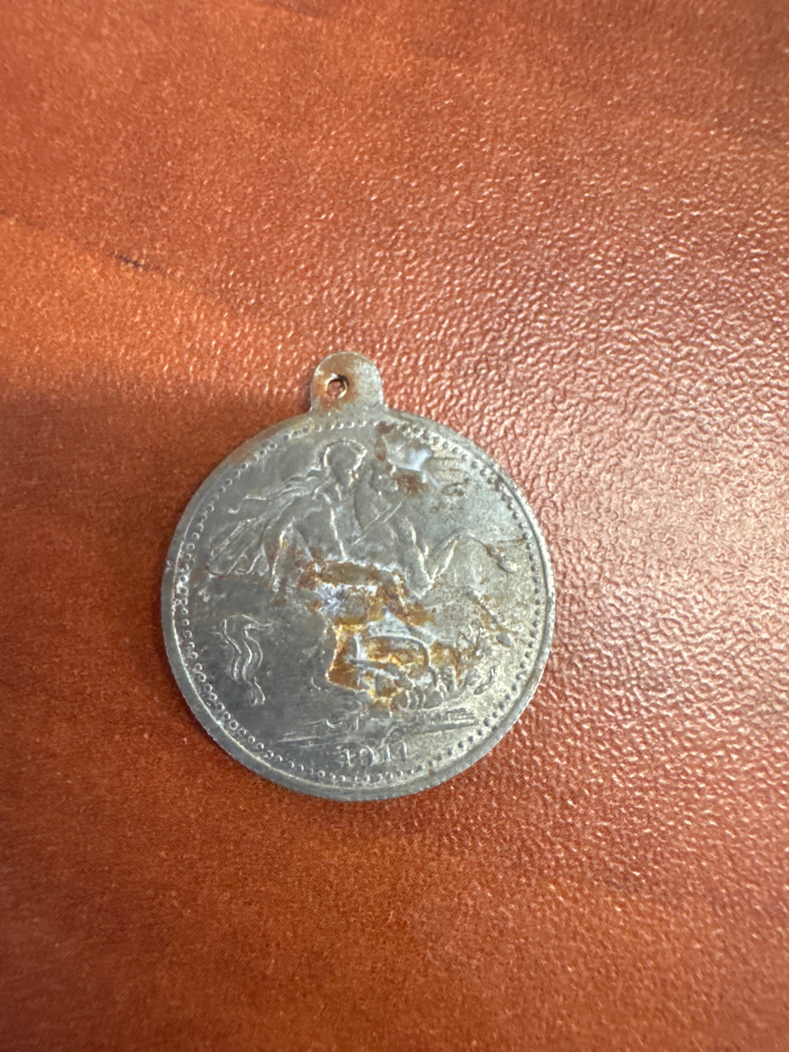1911 Edward VII Coronation Medal: A circular medal featuring a profile of King Edward VII on one side and a depiction of St. George slaying the dragon on the other. The medal has a small loop for suspension and shows signs of age and 