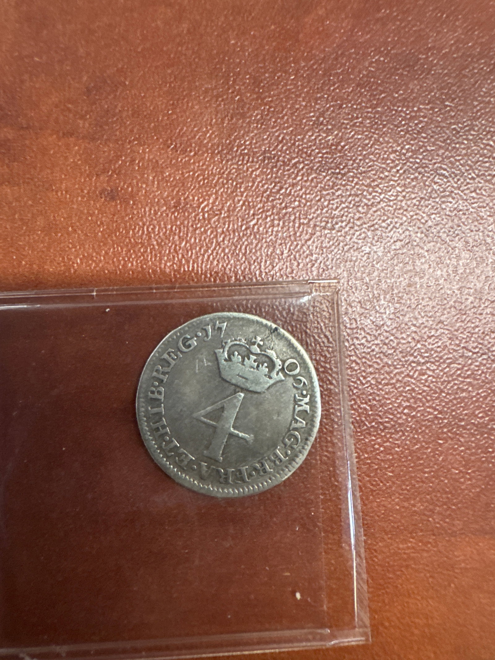 1706 Great Britain 4 Pence Coin: A silver 1706 Great Britain 4 Pence coin featuring Queen Anne on one side and the royal crest on the other. The coin shows signs of wear consistent with its age.