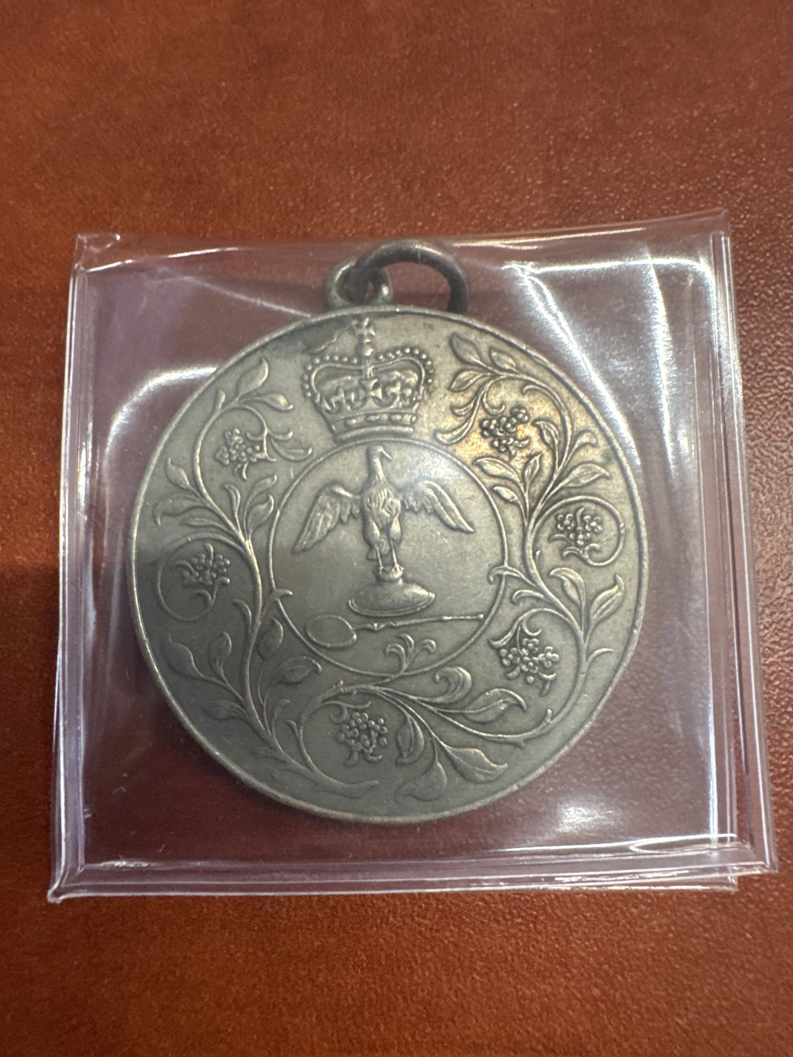1977 Silver Jubilee Medal Elizabeth II: A commemorative medal from 1977 celebrating the Silver Jubilee of Queen Elizabeth II. One side features a crowned eagle emblem surrounded by floral motifs, and the other side depicts Queen Elizabeth I