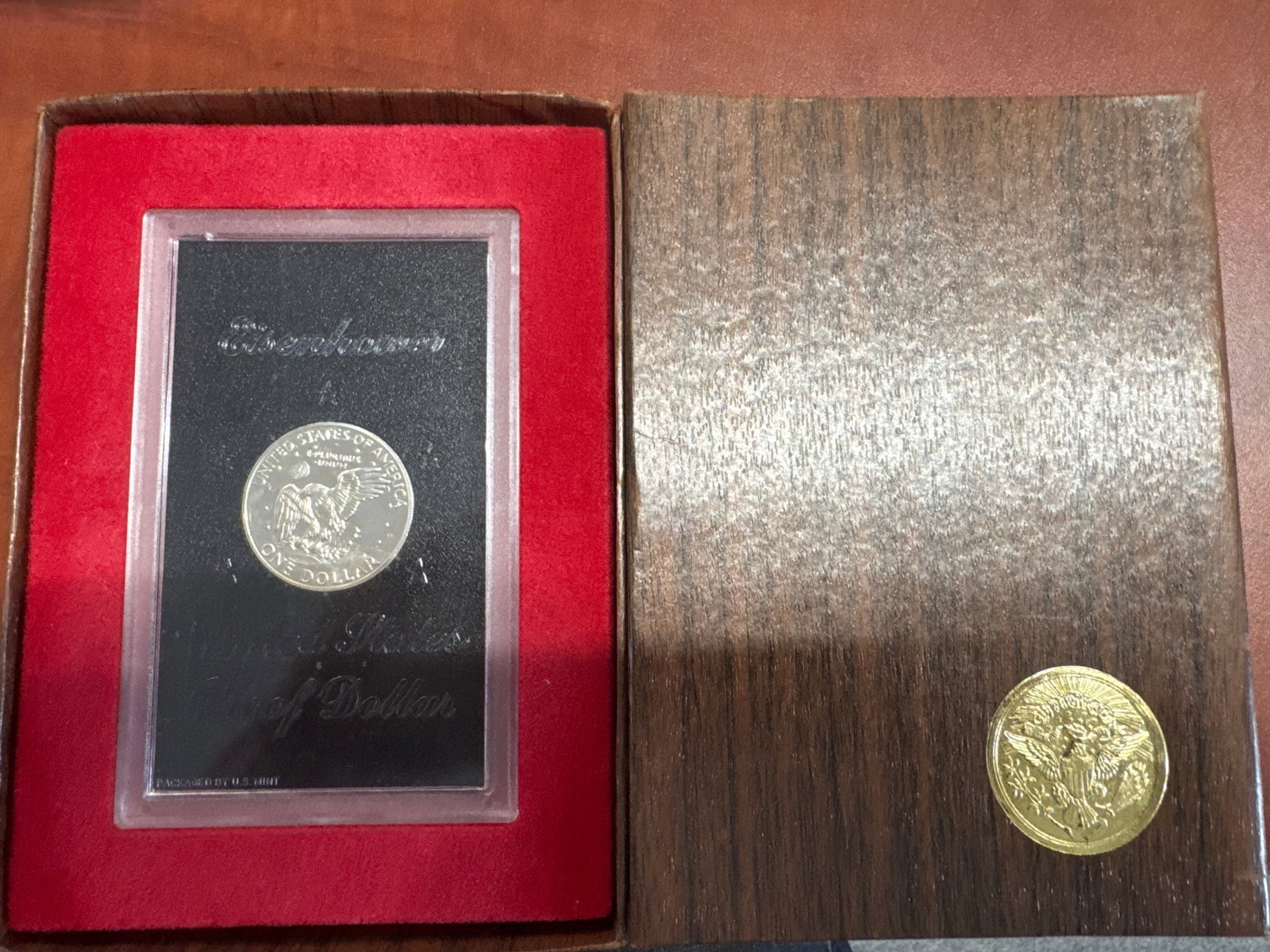 1971 Eisenhower Dollar Coin in Presentation Case: This lot features a 1971 Eisenhower Dollar coin, presented in a red velvet-lined case with a black insert. The coin is displayed in a protective plastic holder, showcasing the obverse with President E