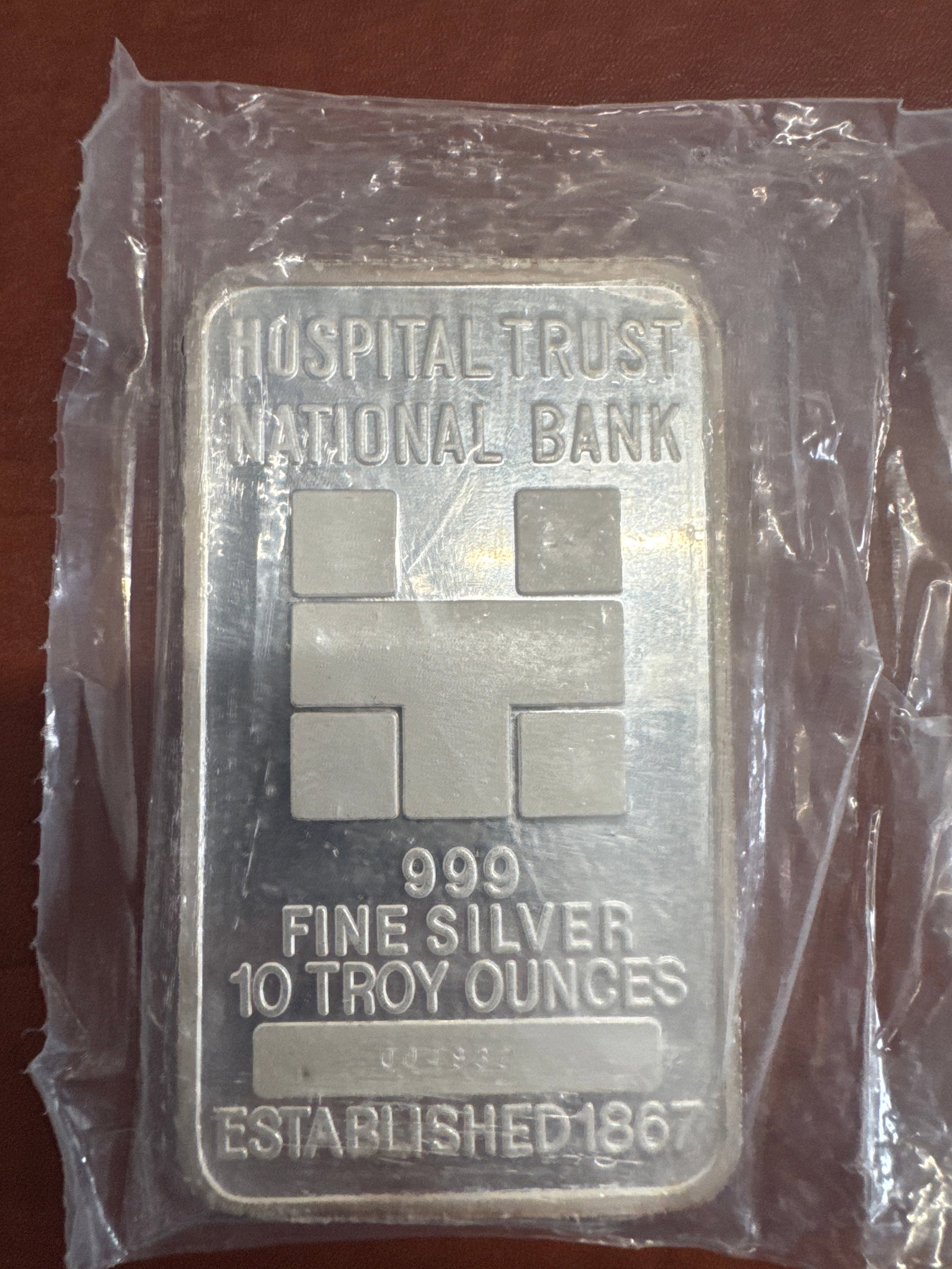 Hospital Trust National Bank 10 Troy Ounces 999 Fine Silver Bar: A 10 troy ounce bar of 999 fine silver from Hospital Trust National Bank, established in 1867. The obverse features the bank's name and logo, along with the silver purity and weight. The reverse h