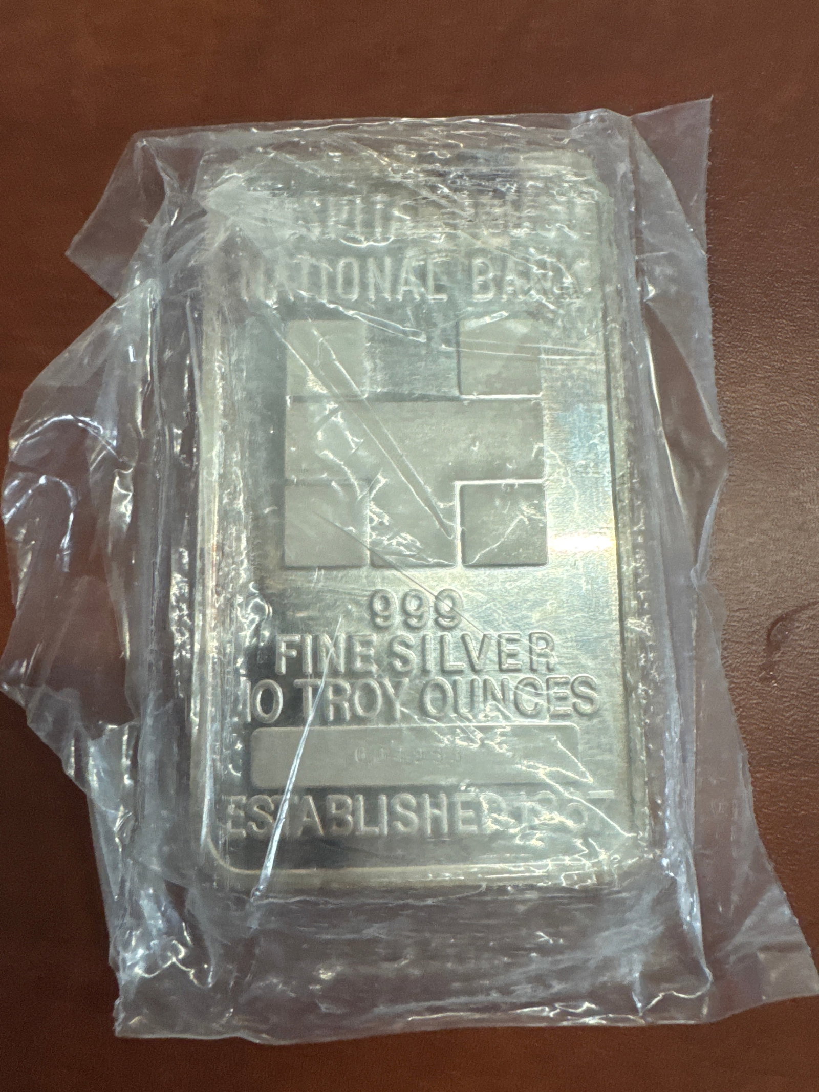 10 Troy Ounce 999 Fine Silver Bar - National Bank: This is a 10 troy ounce bar of 999 fine silver, manufactured by National Bank. The bar features a repeating geometric pattern on one side and the National Bank logo and specifications on the other. It
