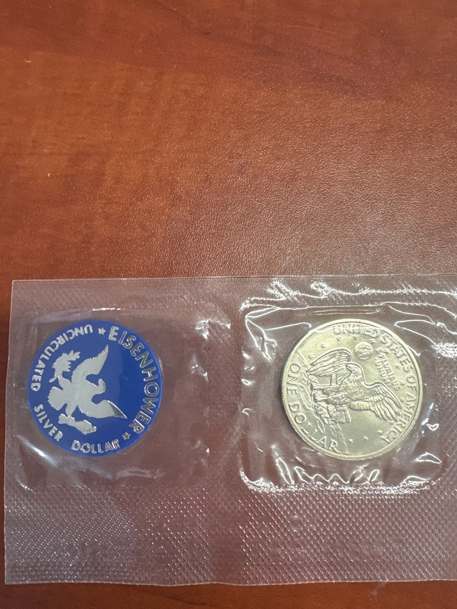 1972 Eisenhower Silver Dollar Coin: This lot features a 1972 Eisenhower Silver Dollar coin, encapsulated in protective plastic. The coin is uncirculated and made of silver. The obverse features a profile of Dwight D. Eisenhower, and the