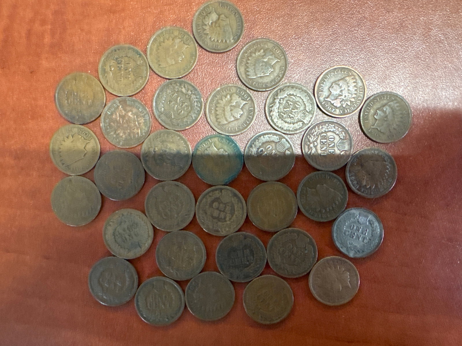 Collection of Indian Head Pennies: A collection of Indian Head pennies, dating from the late 19th and early 20th centuries. Some coins show clear dates and designs, while others exhibit wear.