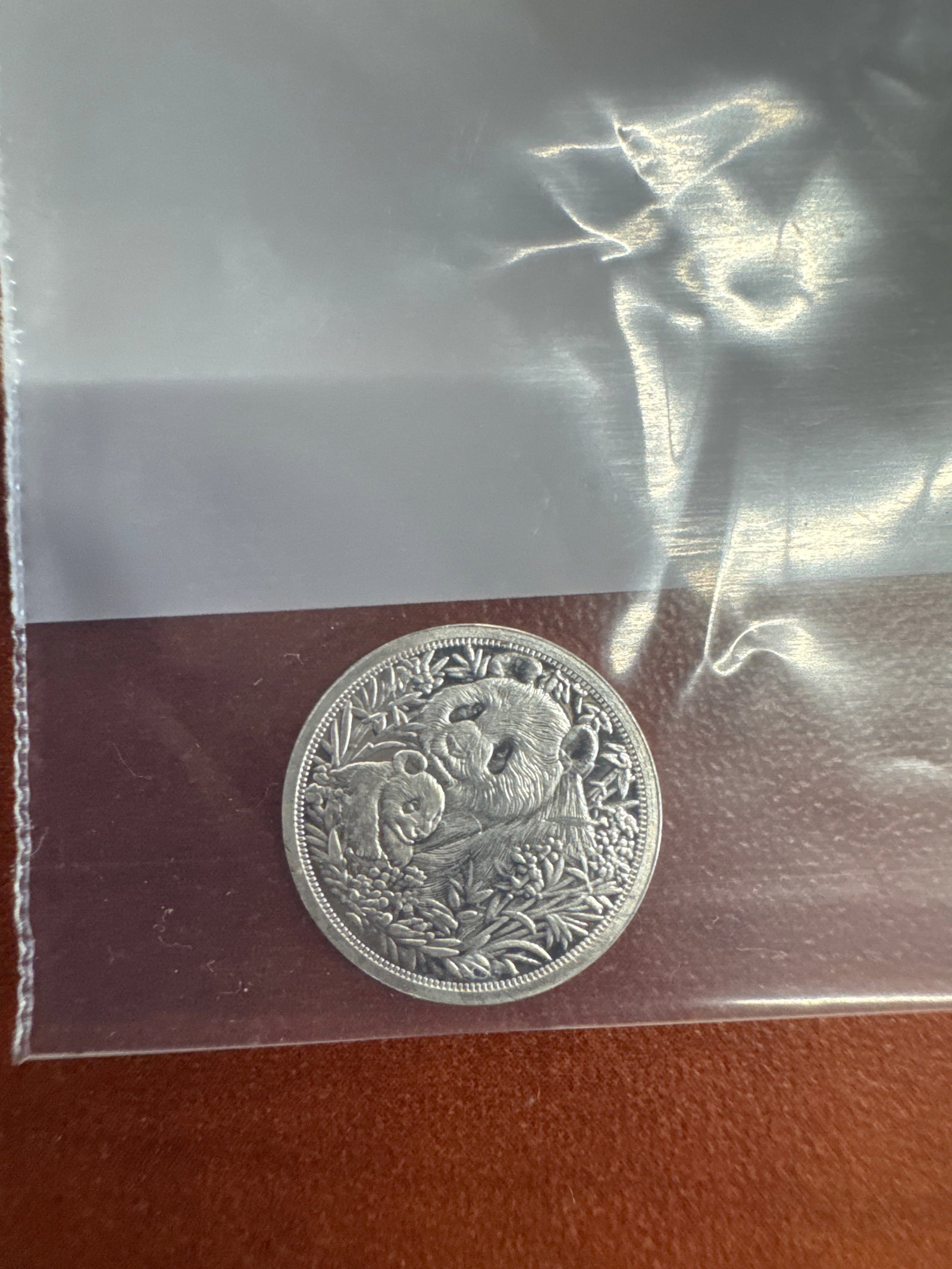 Lotus Mint 1 Gram .999 Fine Silver Coin: This Lotus Mint coin is made of 1 gram of .999 fine silver. The obverse features a lotus flower design, and the reverse depicts a panda bear surrounded by foliage.