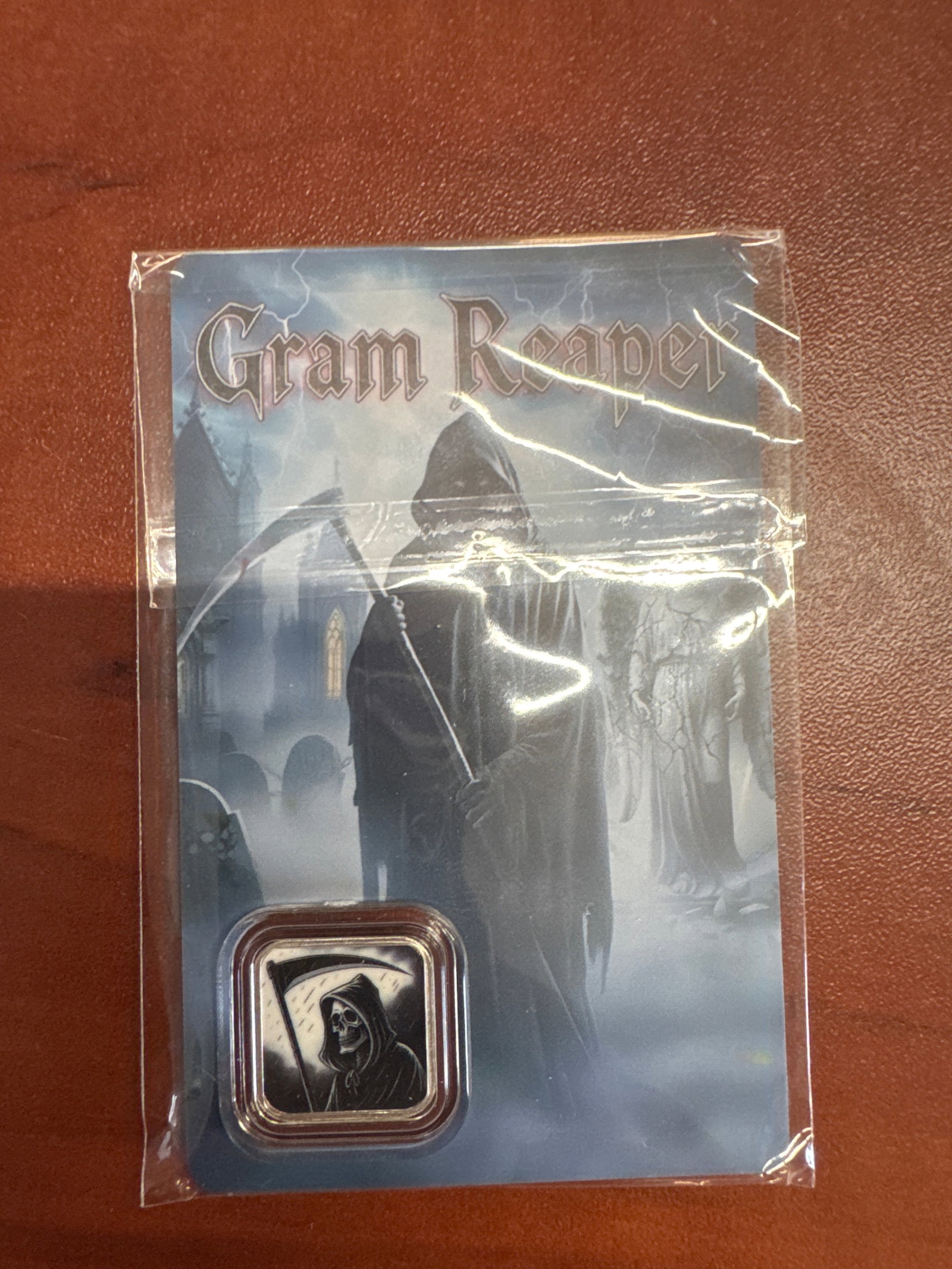 Gram Reaper 1 Gram .999 Fine Silver Coin: This collectible features a 1-gram .999 fine silver coin with a "Gram Reaper" theme. The coin has a diameter of 16mm and a mintage of 32,000. It comes in protective packaging with a serial n