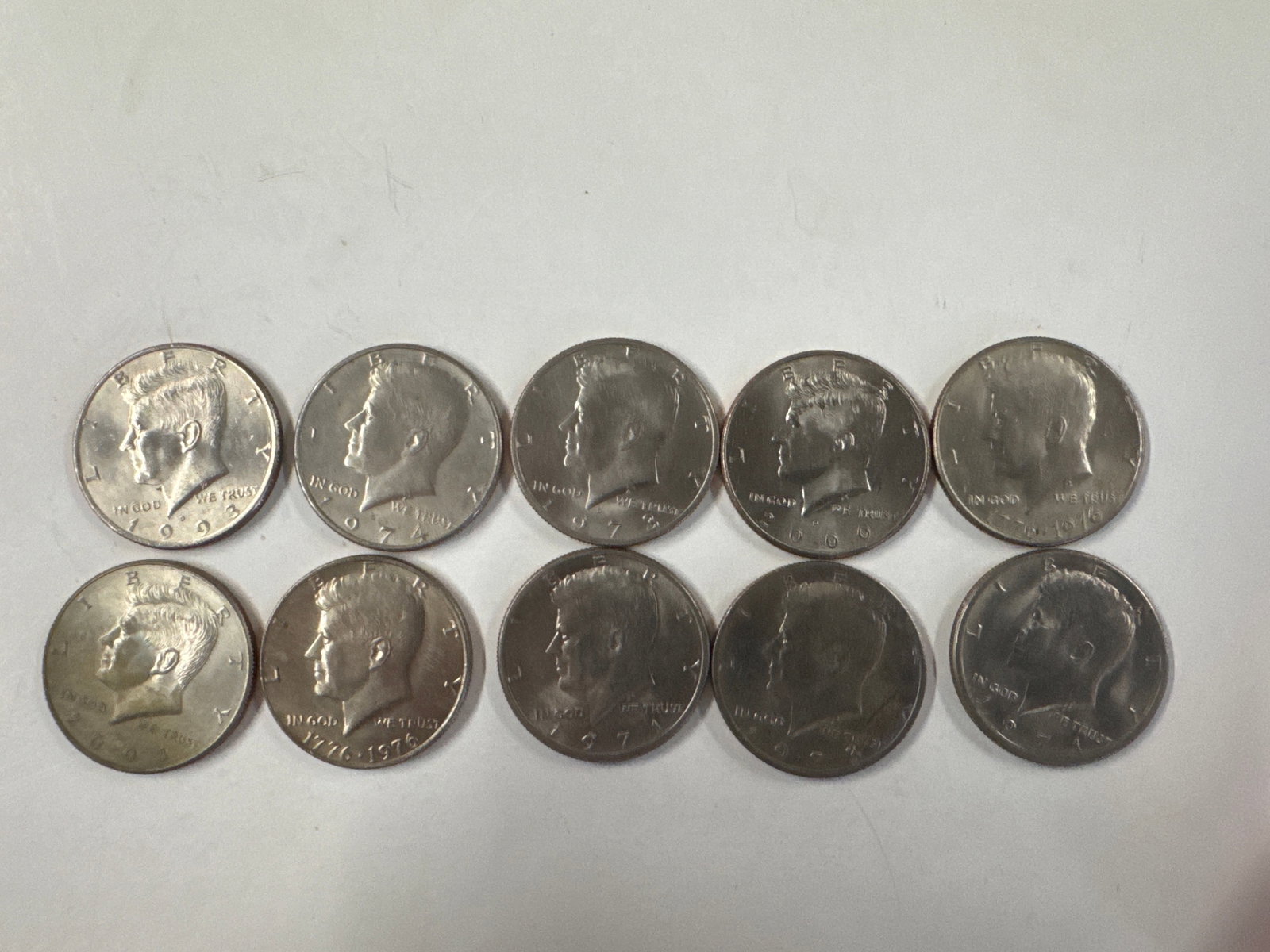 Collection of 10 Kennedy Half Dollar Coins (1): This lot features a collection of ten Kennedy Half Dollar coins. The obverse displays the profile of John F. Kennedy, while the reverse depicts the Presidential Seal. The coins appear to be in circula
