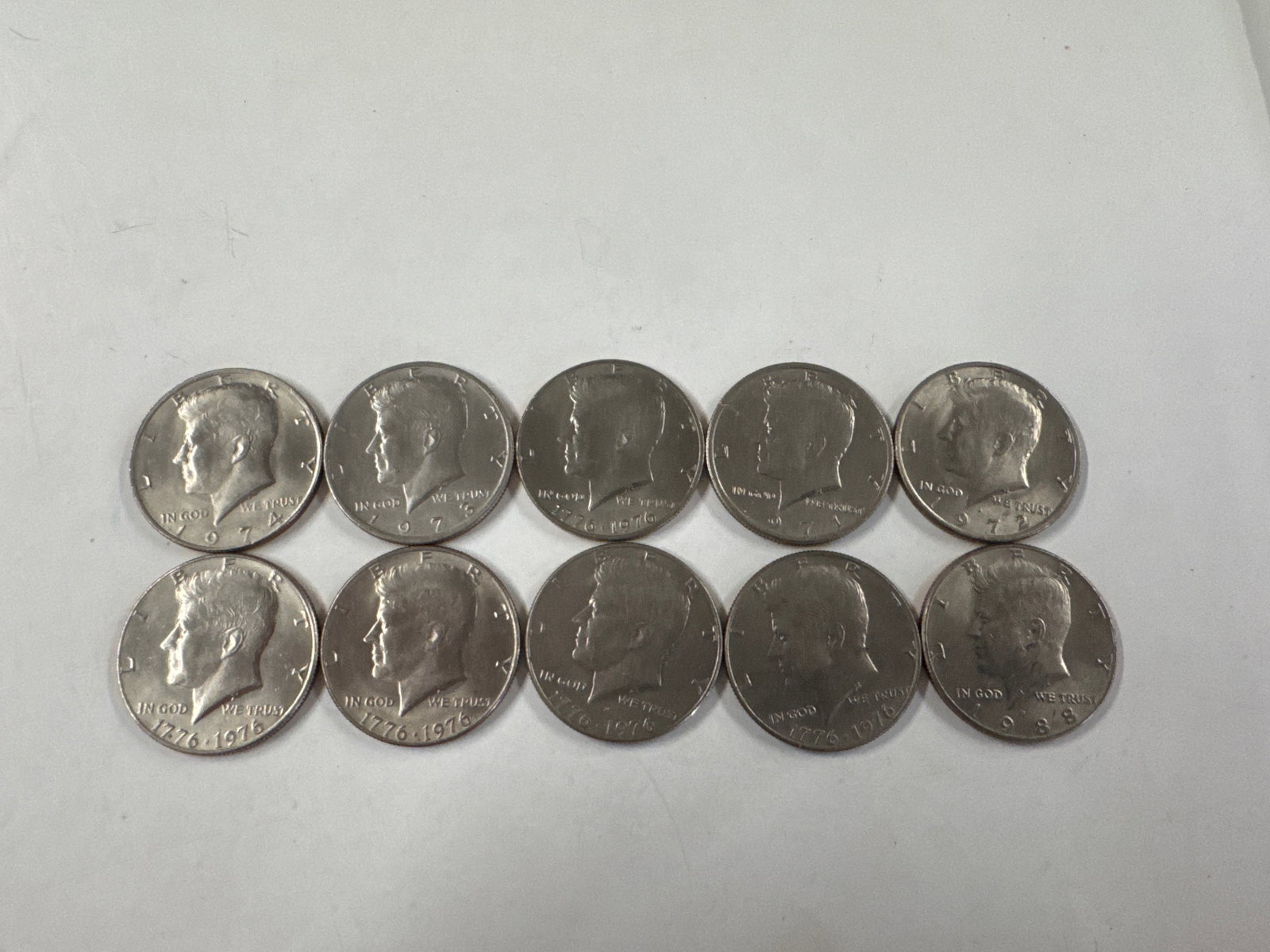 Collection of Ten Kennedy Half Dollar Coins: This lot features ten Kennedy half dollar coins. The obverse displays the profile of John F. Kennedy, while the reverse depicts the Presidential Seal.