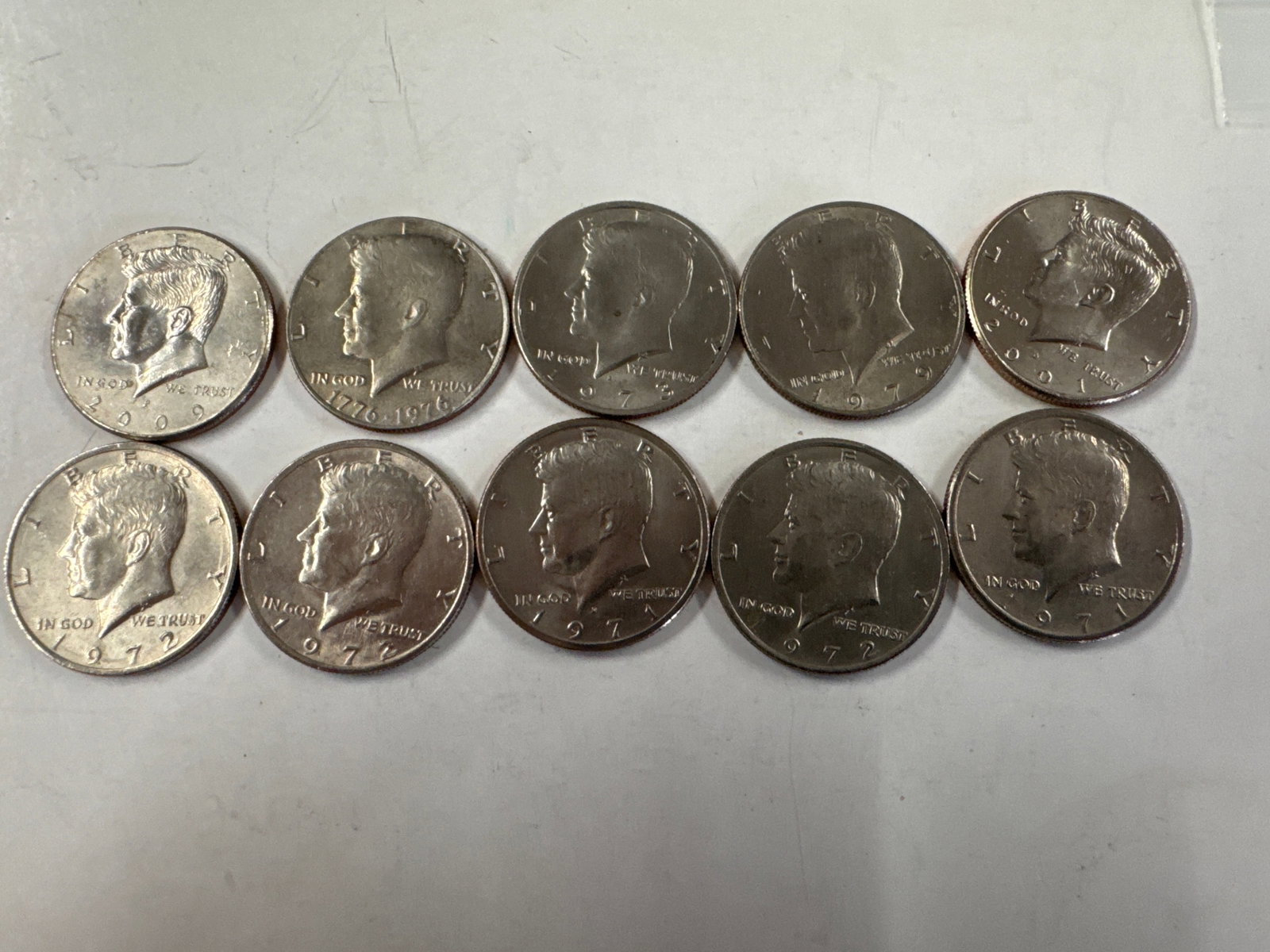 Collection of 10 Kennedy Half Dollar Coins: This lot features a collection of ten Kennedy half dollar coins. The obverse of each coin displays a profile of John F. Kennedy, while the reverse showcases the Presidential Seal.