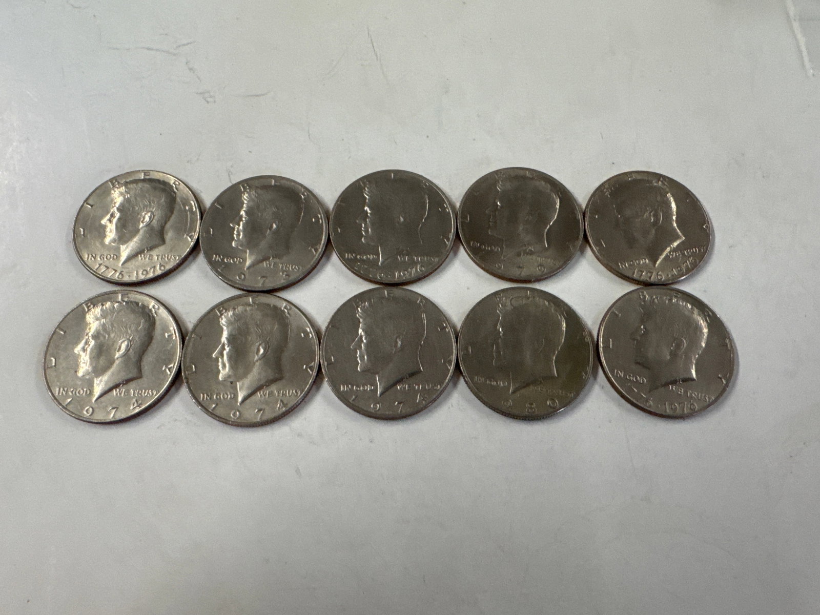 Collection of Ten Kennedy Half Dollar Coins: This lot features ten Kennedy half dollar coins. The obverse displays a profile of John F. Kennedy, while the reverse depicts Independence Hall. 