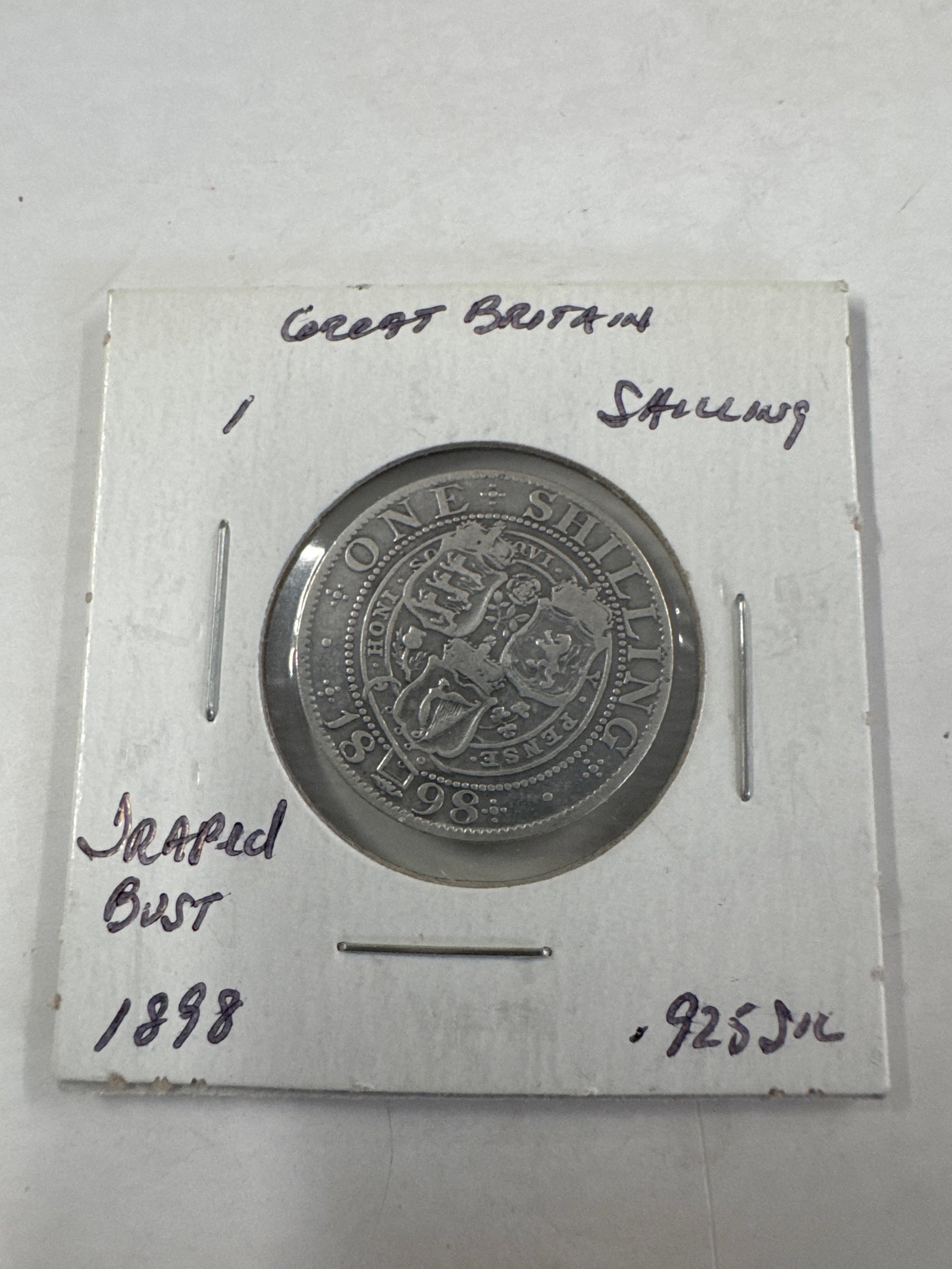 Great Britain 1898 One Shilling Coin - Victoria: A silver coin from Great Britain, dated 1898. The obverse features a draped bust of Queen Victoria, with the inscription 'VICTORIA DEI GRA BRITT REGINA IND IMP'. The reverse displays the