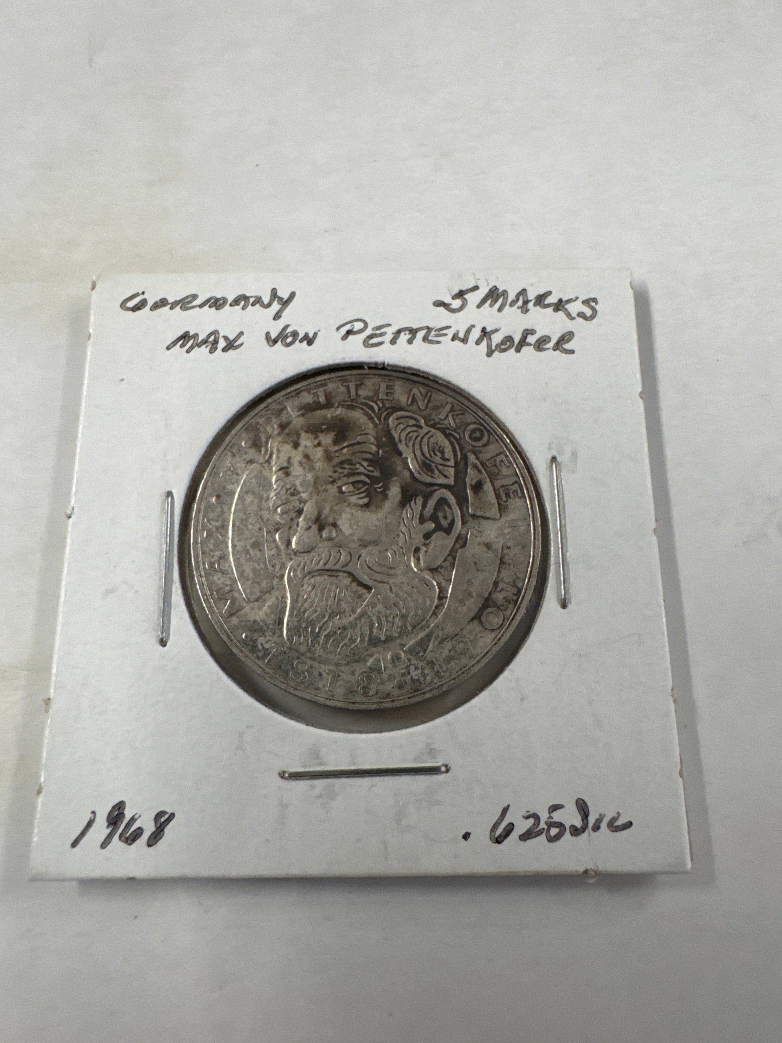 Germany 5 Marks Coin - Max von Pettenkofer - 1968: A 1968 German 5 Marks coin featuring a portrait of Max von Pettenkofer on one side and the German eagle on the other. The coin is housed in a protective cardboard holder.