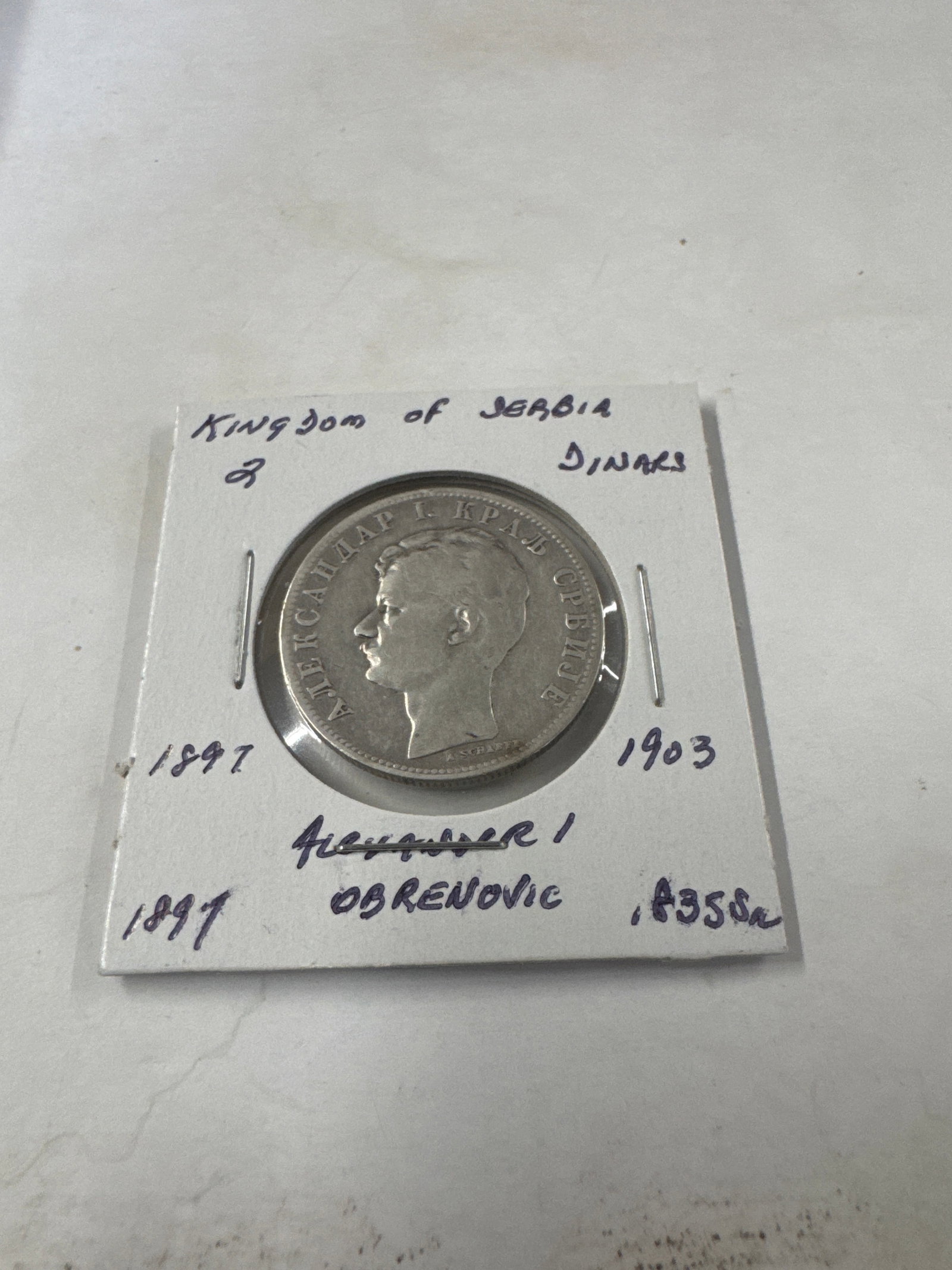 1897 Kingdom of Serbia 2 Dinara Coin of Alexander I Obrenovic: A silver 2 Dinara coin from the Kingdom of Serbia, dated 1897. The obverse features a profile portrait of King Alexander I Obrenovic. The reverse displays the denomination '2 DINARA' within a 