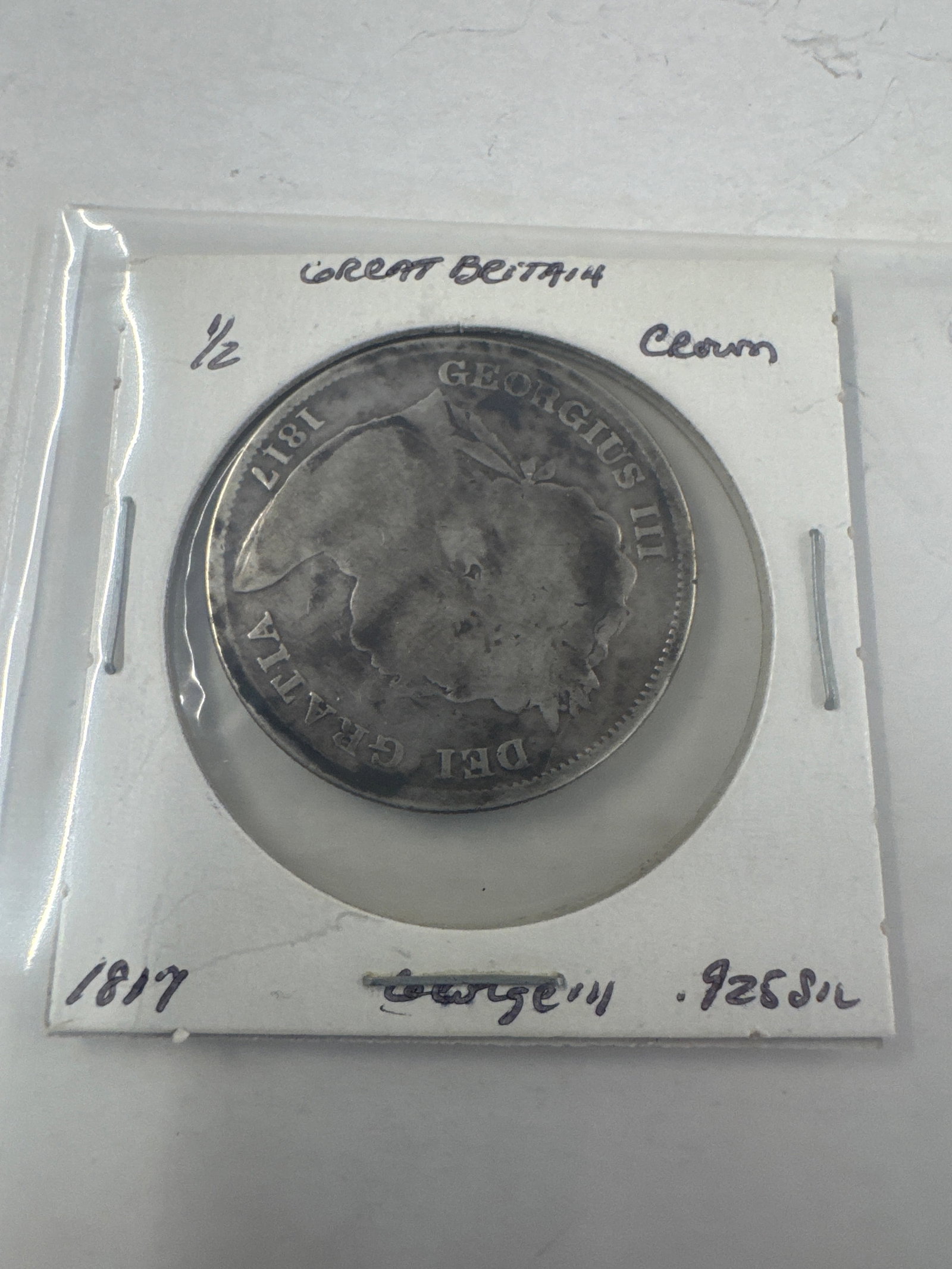 1817 Great Britain 1/2 Crown Coin - George III: A silver 1817 Great Britain half crown coin featuring King George III. The obverse displays the profile of the king, while the reverse shows the royal coat of arms. 