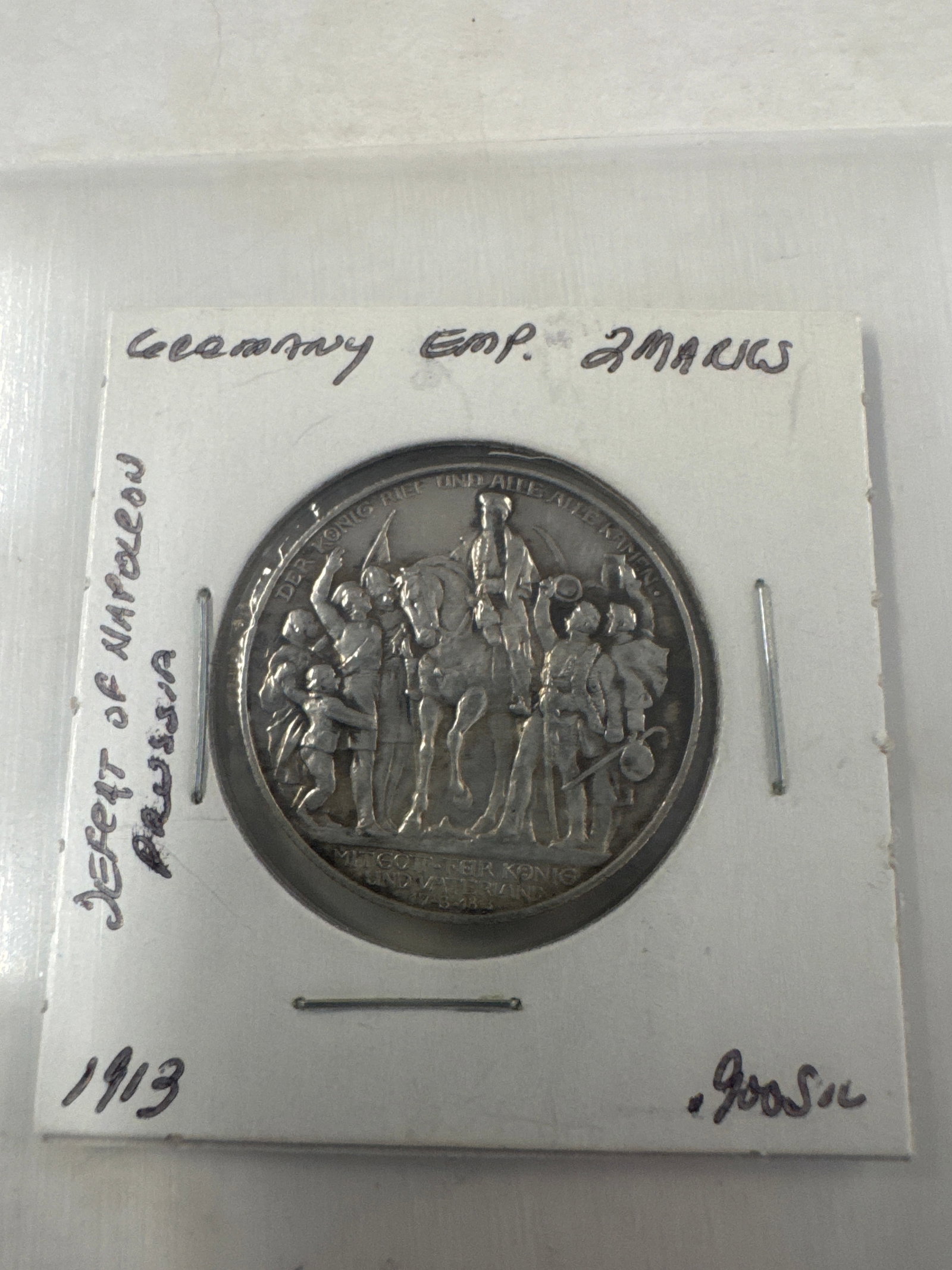 1913 German Empire 2 Mark Coin - Defeat of Napoleon Prussia: A silver 1913 German Empire 2 Mark coin commemorating the defeat of Napoleon in Prussia. The obverse features an eagle with a serpent, and the reverse depicts a historical scene with a central figure 