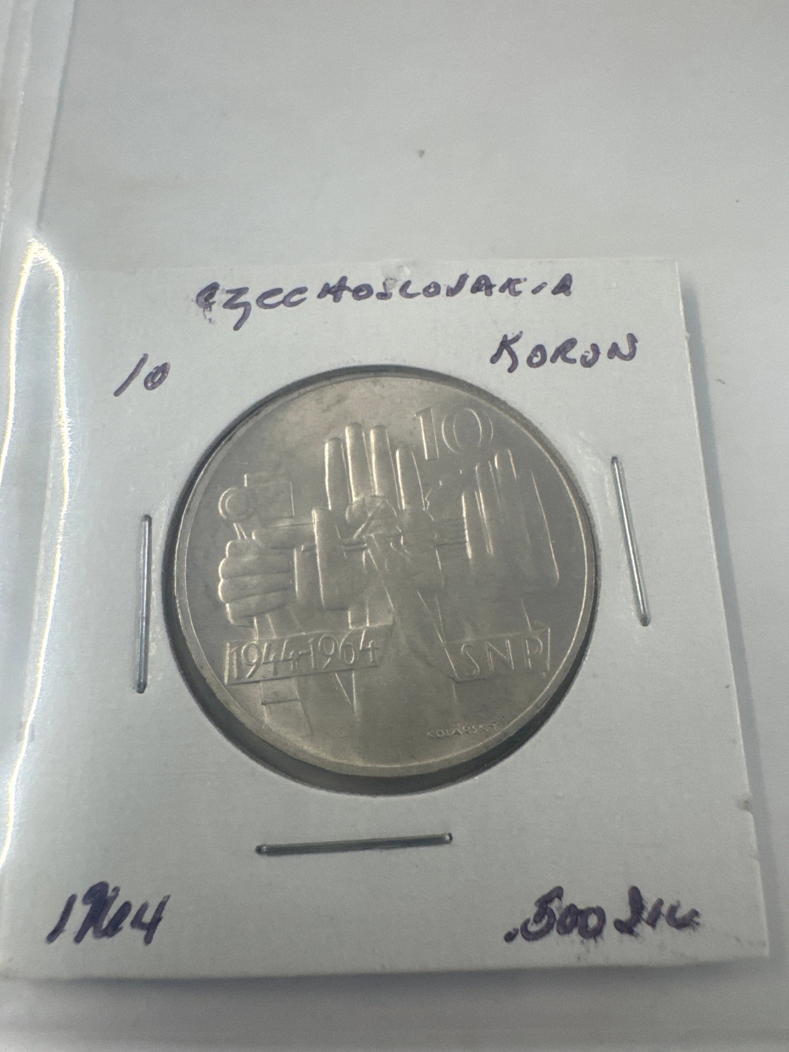 1964 Czechoslovakia 10 Korun Coin: A 1964 Czechoslovakian 10 Korun coin featuring a socialist realist design on one side and the national coat of arms on the other. The coin commemorates the 20th anniversary of the Slovak National Upri