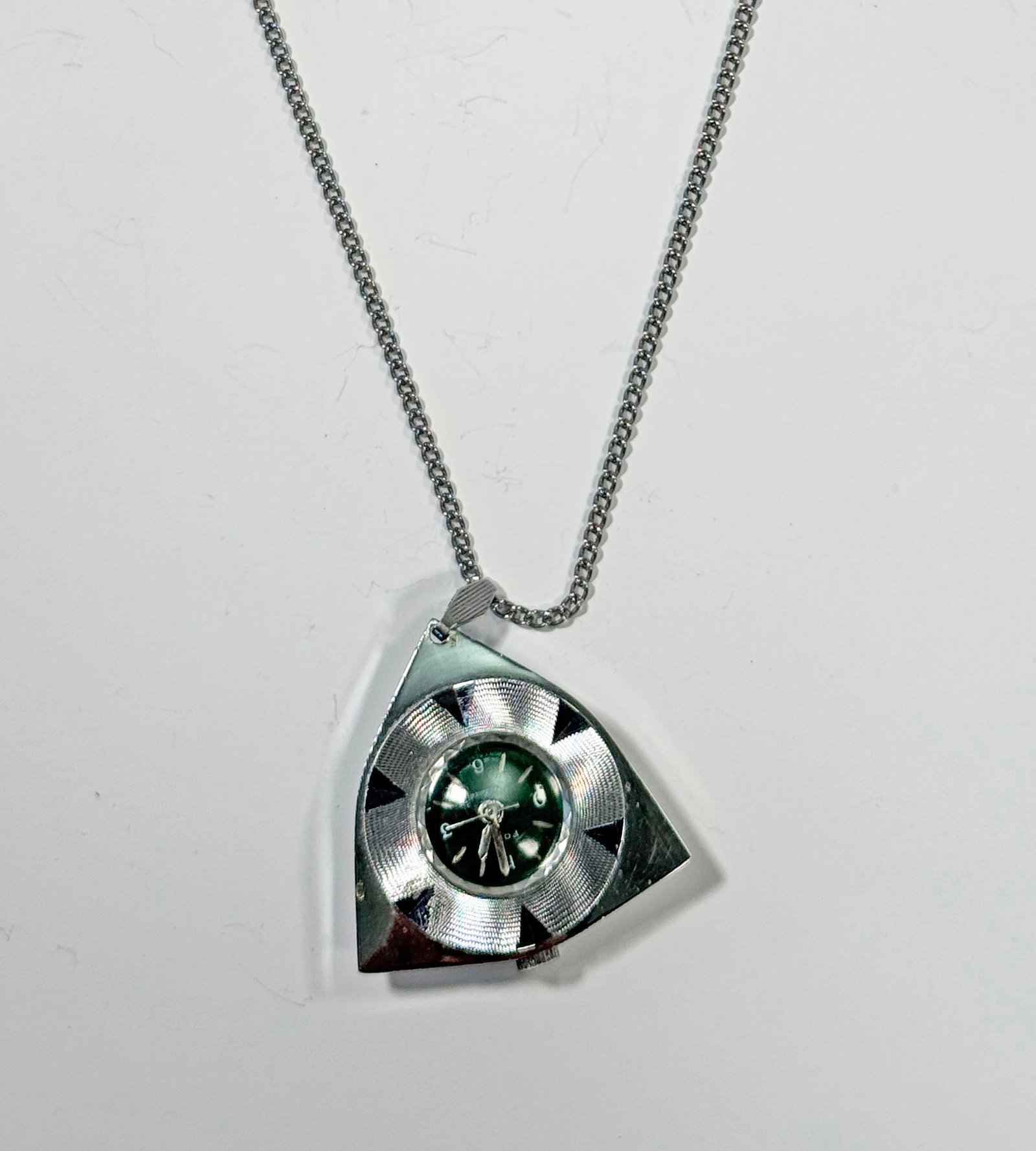 Focal Deluxe Pendant Watch Necklace: Focal Deluxe pendant watch necklace. The watch face is green and set in a silver tone, shield shaped pendant. The chain is silver tone. Swiss movement, Hong Kong dial. Not currently running, may need 