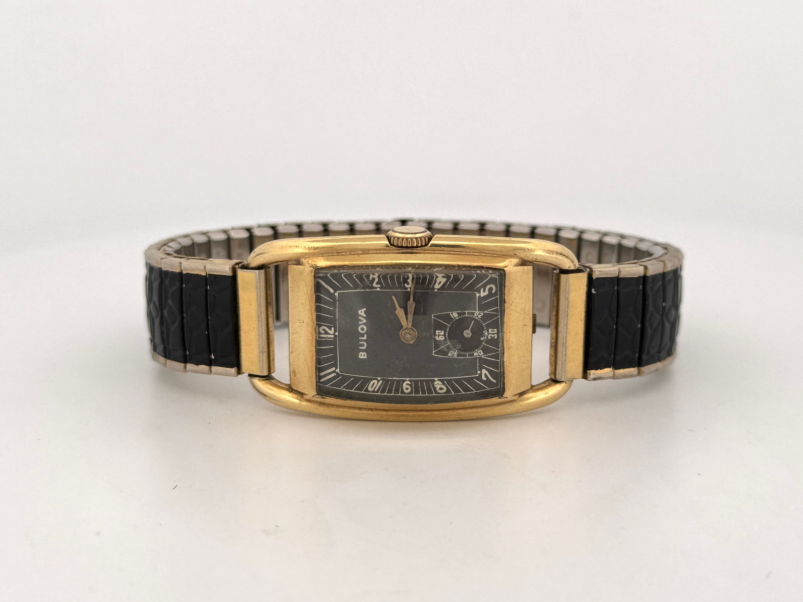 Bulova Gold FIlled Art Deco Rectangular Wristwatch: Vintage Bulova wristwatch featuring a gold filled rectangular case and a black dial. The watch has an expansion band with black and gold-tone links. Watch head size: 4.3 x 2.2 cm approx. 