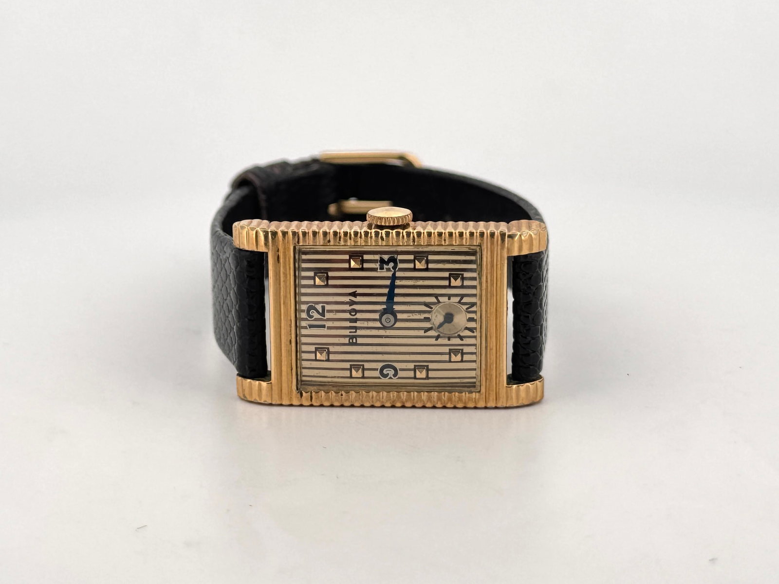 Bulova Rectangular Golf Filled Art Deco Wristwatch: Gilt rectangular Bulova wristwatch featuring a striped dial with Arabic numerals and a subsidiary seconds dial. Fitted with a black leather strap. Watch head size: 3.6 x 2.1 cm approx. 