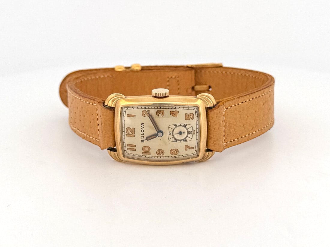 Vintage Bulova Rolled Gold Tank Wristwatch: A vintage Bulova rolled gold tank wristwatch with a subsidiary seconds dial. The watch features a rectangular case and a tan leather strap. Watch head size: 3.5cm. 