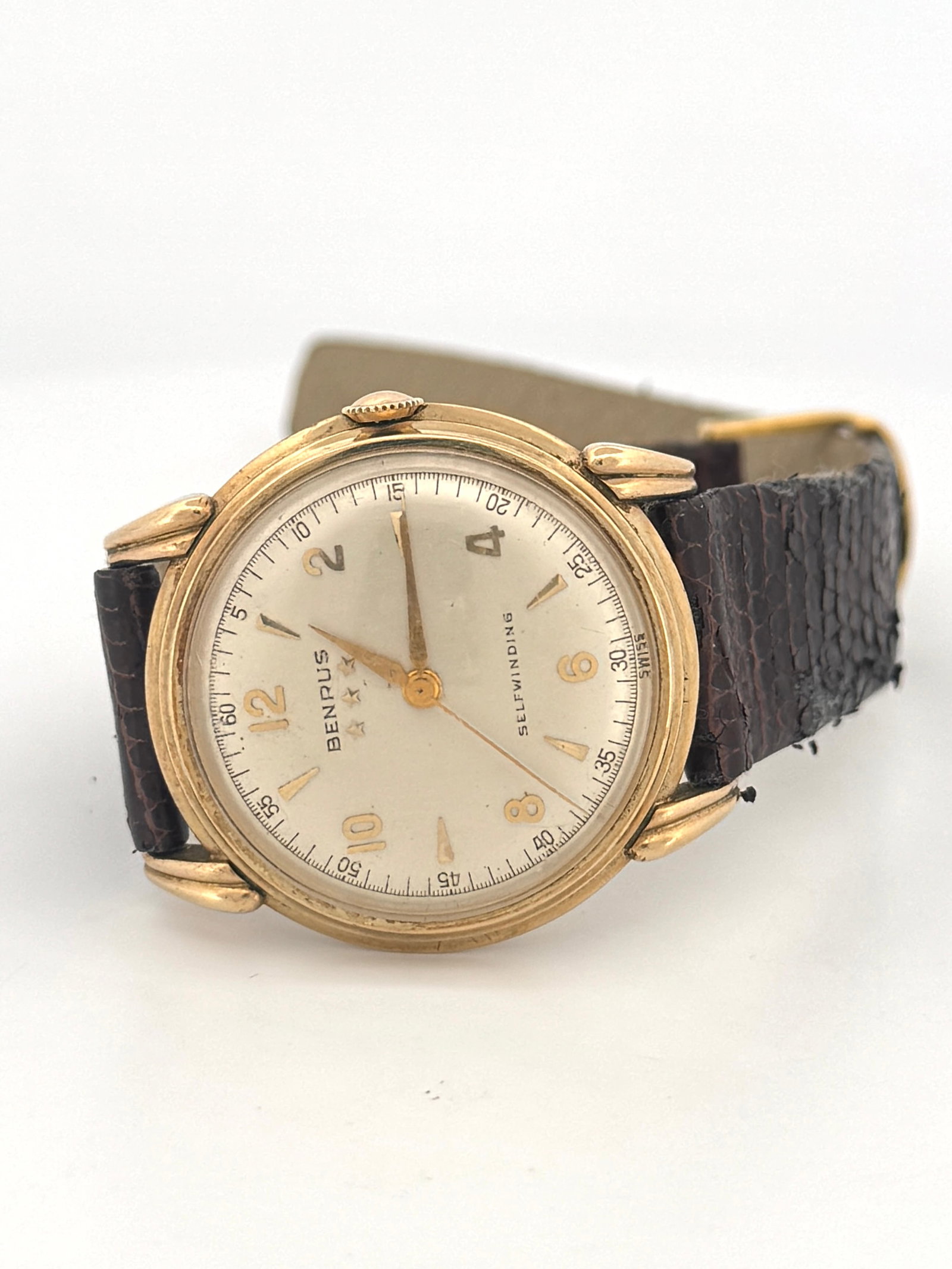 Benrus Selfwinding Gold Tone Wristwatch: Benrus selfwinding wristwatch with a gold tone case and brown lizard grain strap. The watch features a silver tone dial with gold tone hands and markers.