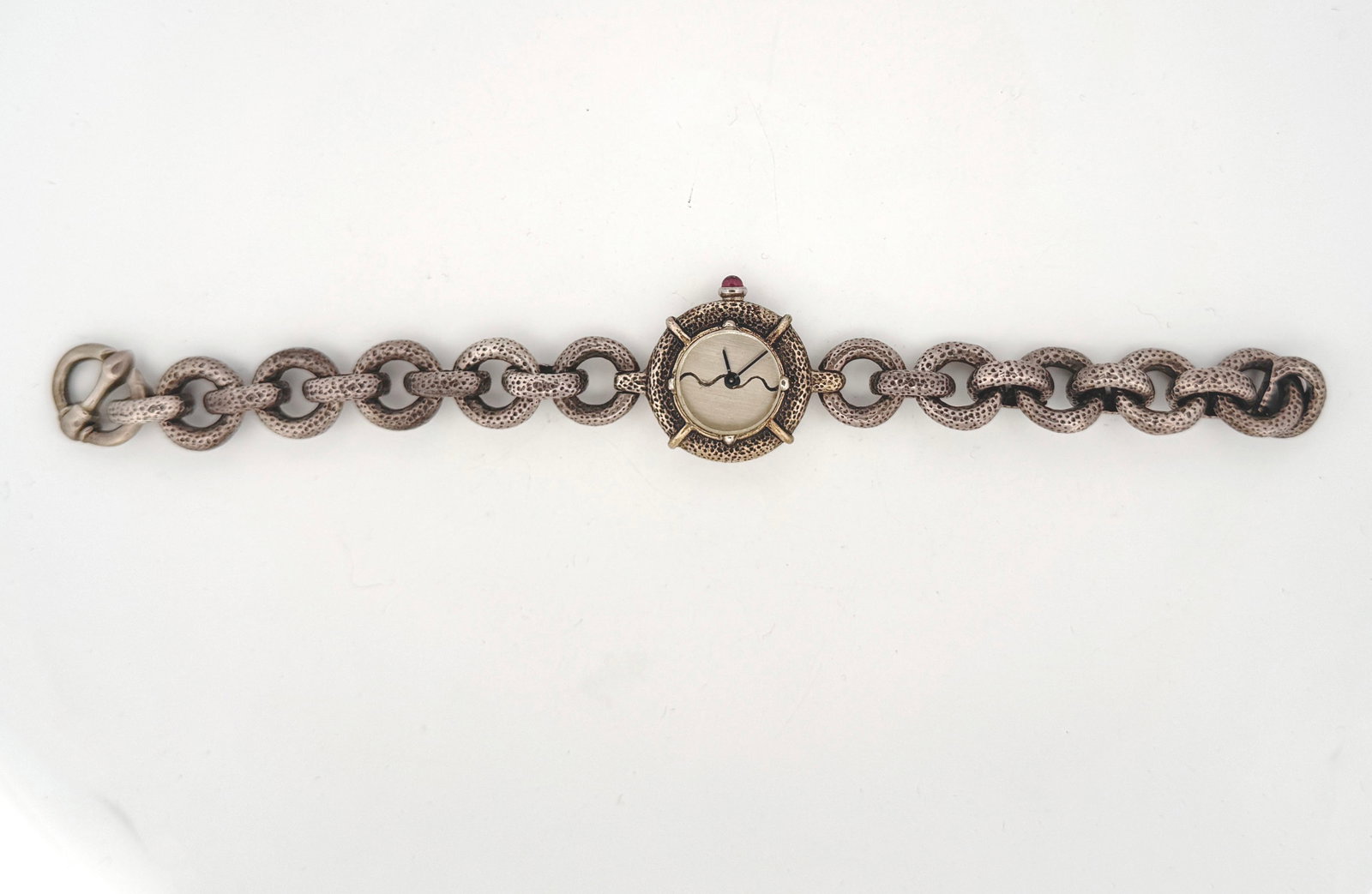 Sterling Silver M Bromberg Watch: A unique sterling silver bracelet watch by m.bromberg. The watch features a textured, chunky link chain and an oval-shaped watch face with a small ruby accent at the top. The back of the watch case is